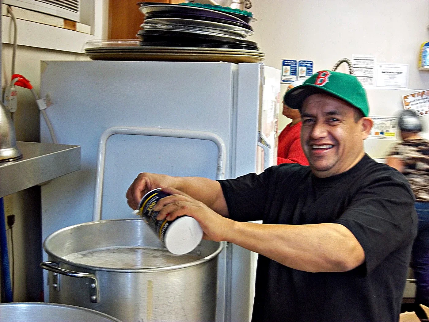 A smiling tamale chef pours salt into a pot