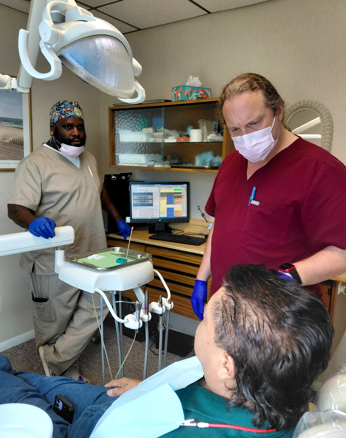 A dentist and another dental professional works with a patient