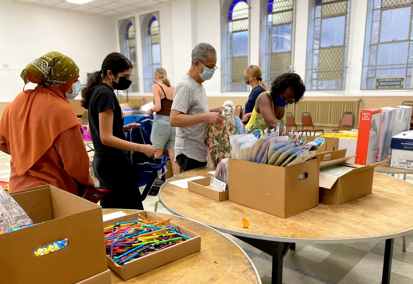 Women and men sort school supplies