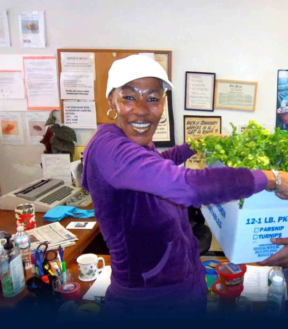 A woman smiling while receiving a box of vegetables