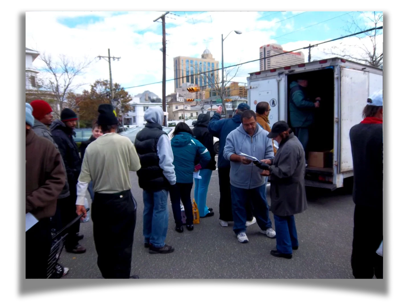 Two people haul supplies out of a box truck to a line of people