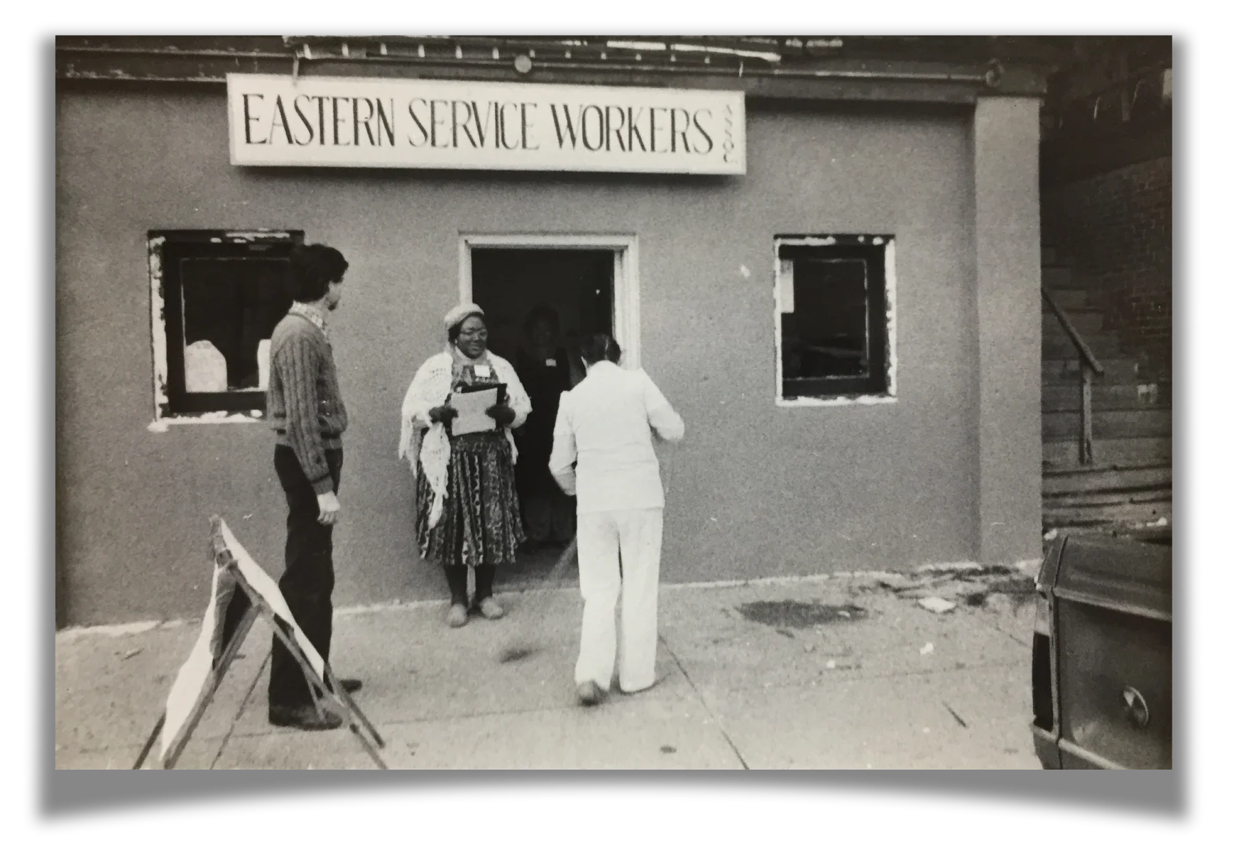 A smiling woman with a clipboard greets people walking into ESWA's office