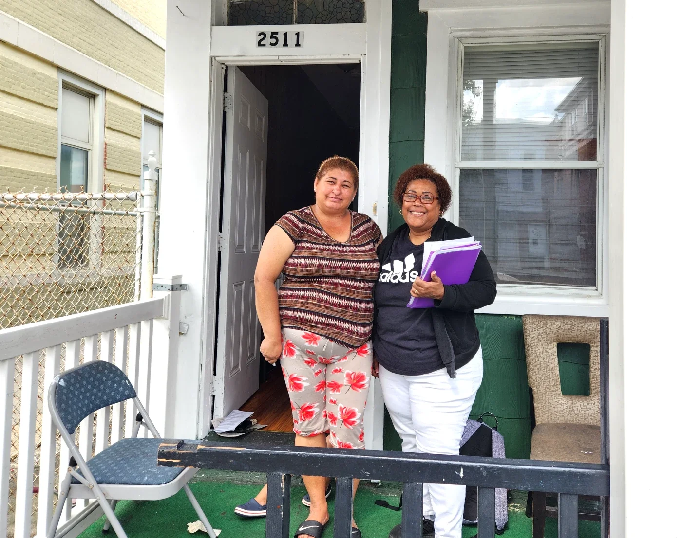 Two women smiling in front of a home