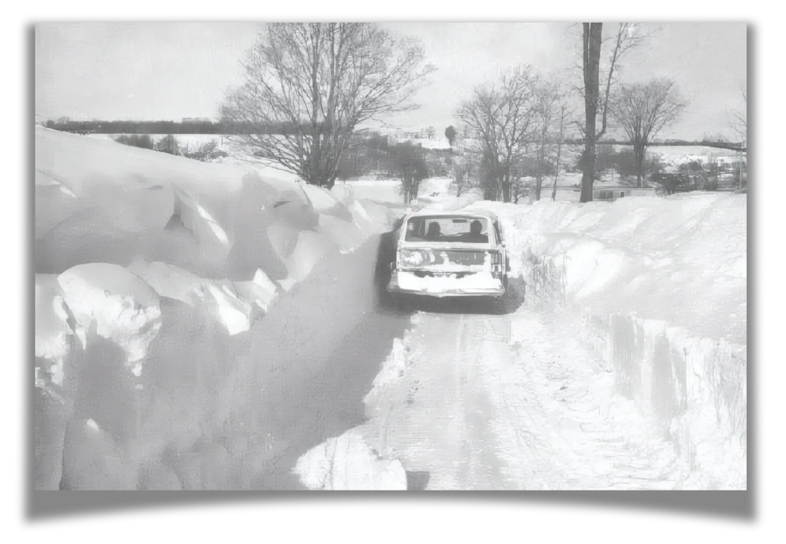 A car driving down a road with piles of snow on either side.