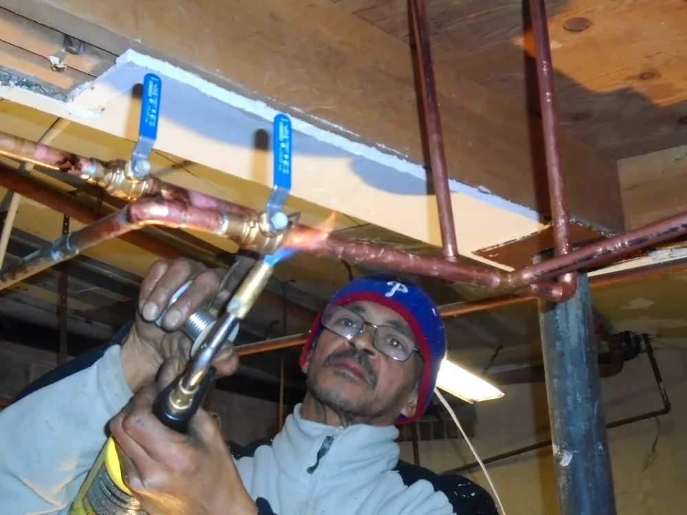 A man with a blowtorch welds a pipe