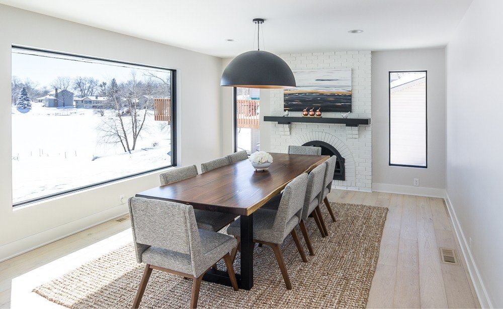modern dining room in Plymouth, MN kitchen remodel. Jute rug, large black and brass pendant light, white brick fireplace.