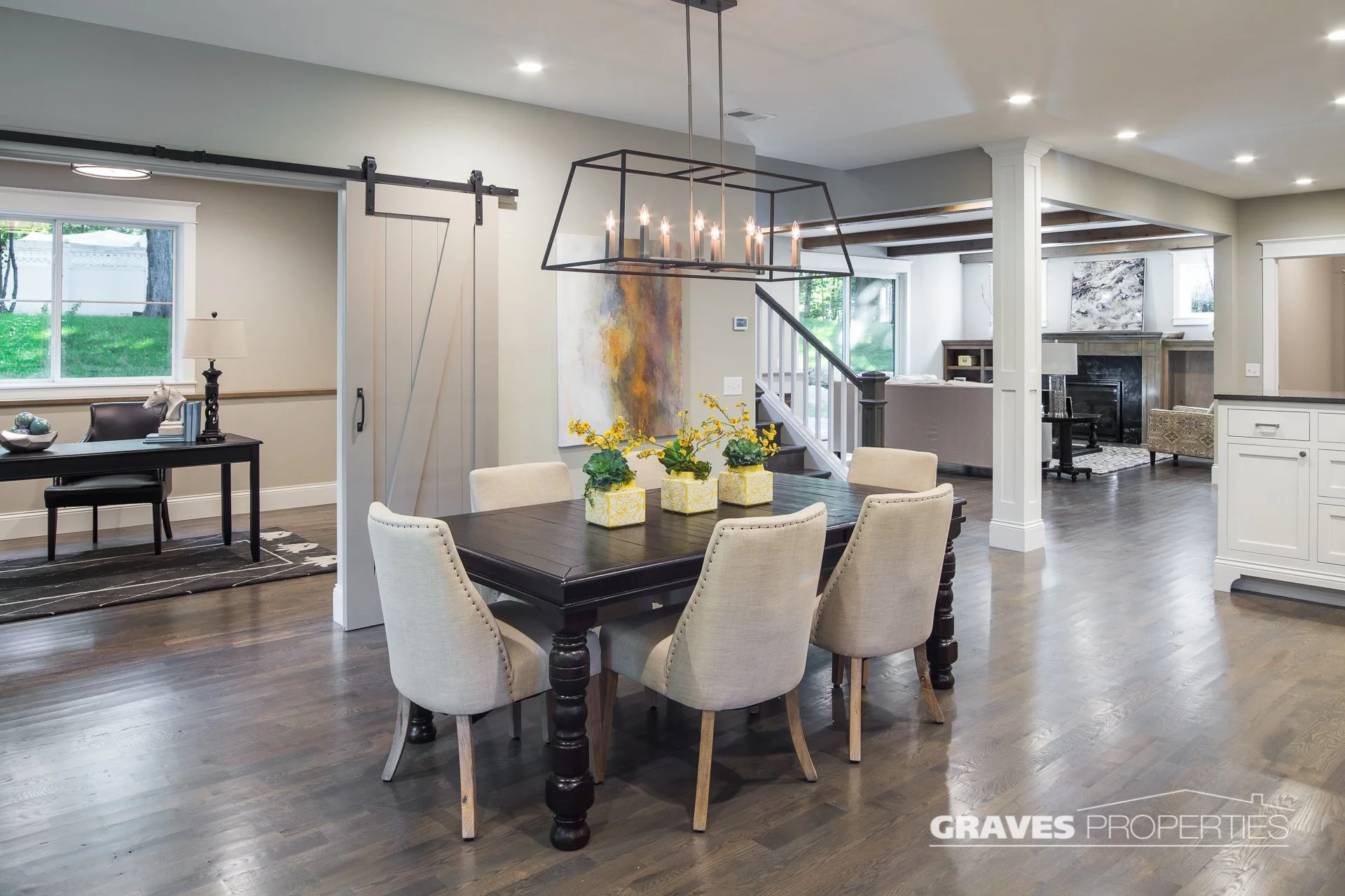 Dining room with candle chandelier, barrel chairs, dark table.