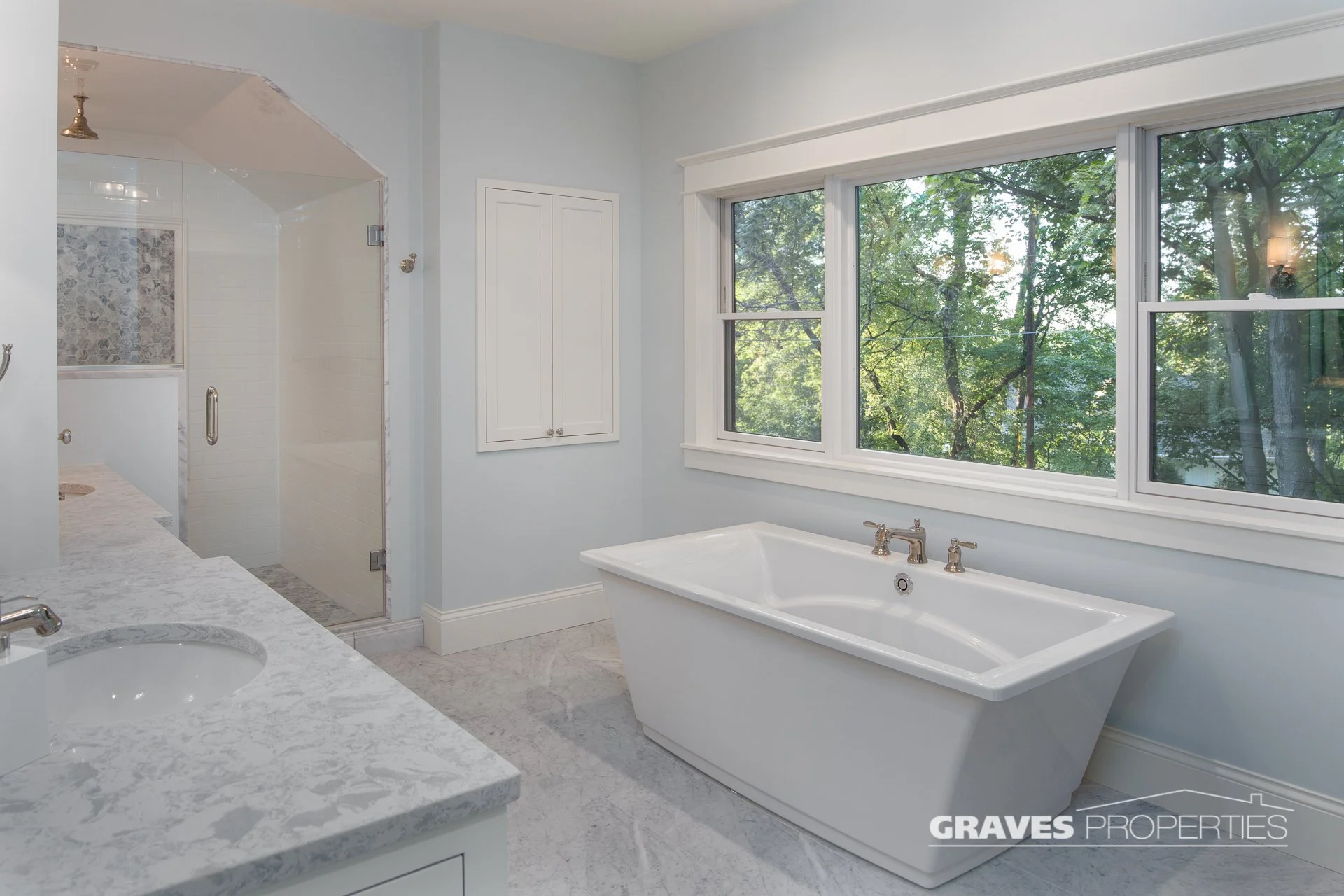 Light blue and white bathroom remodel, soaker tub, white marble shower, polished nickel hardware, Carrara marble countertops.
