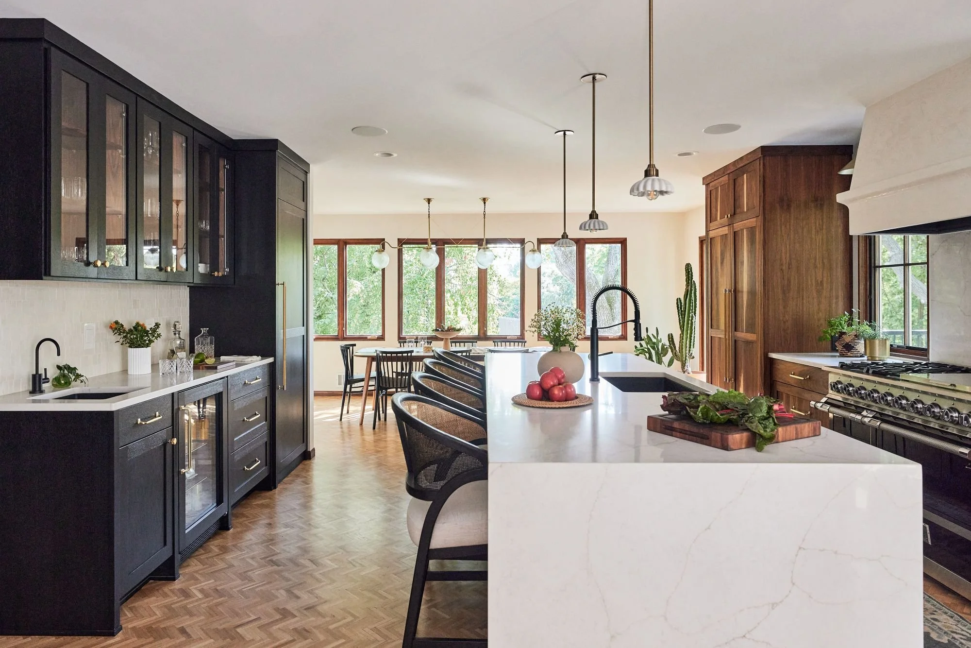 Custom kitchen remodel in Golden Valley, MN, featuring walnut cabinetry, a black island, butcher block prep surface and herringbone wood floors.