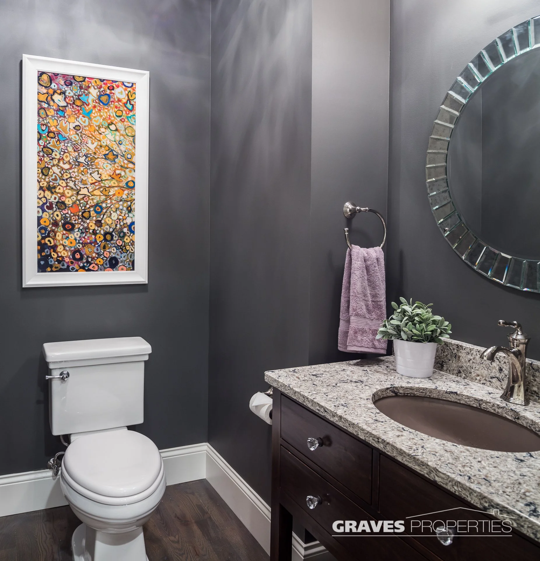 powder room with charcoal walls granite countertops, colorful art above the toilet.