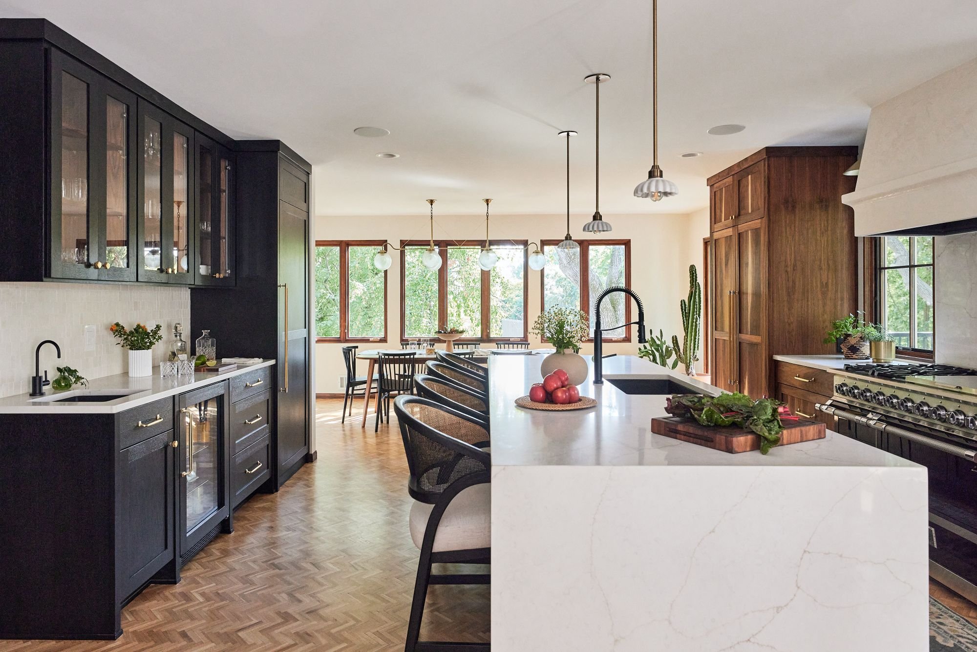 Golden Valley custom kitchen remodel, walnut custom cabinetry and oak stained black cabinets, brass hardware and quartz countertops. a plaster hood above a professional range.