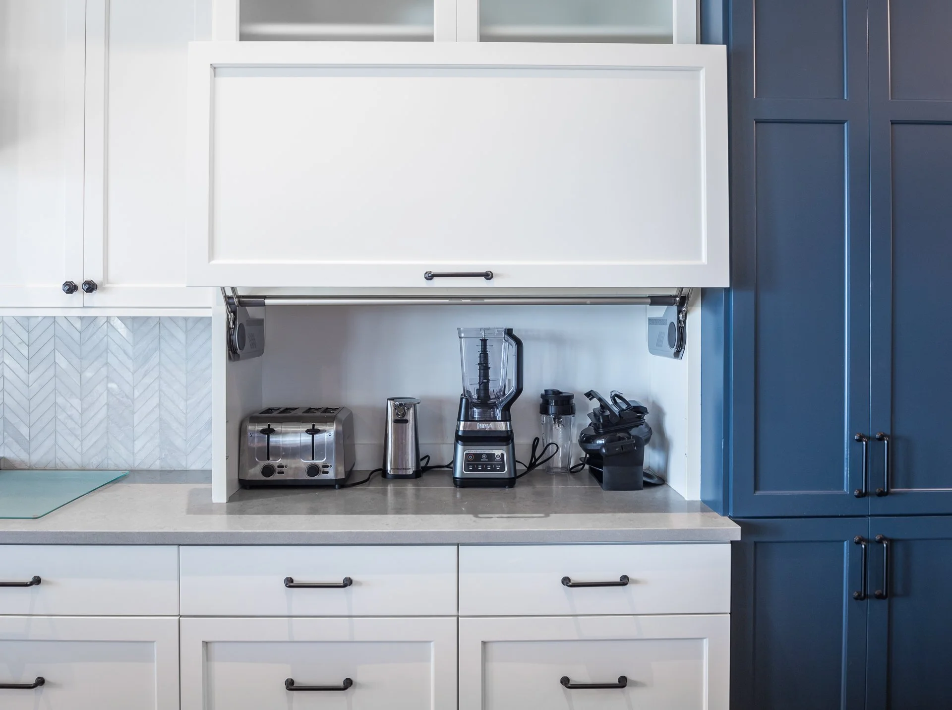 White appliance garage cabinet with lift-up door and navy custom cabinetry