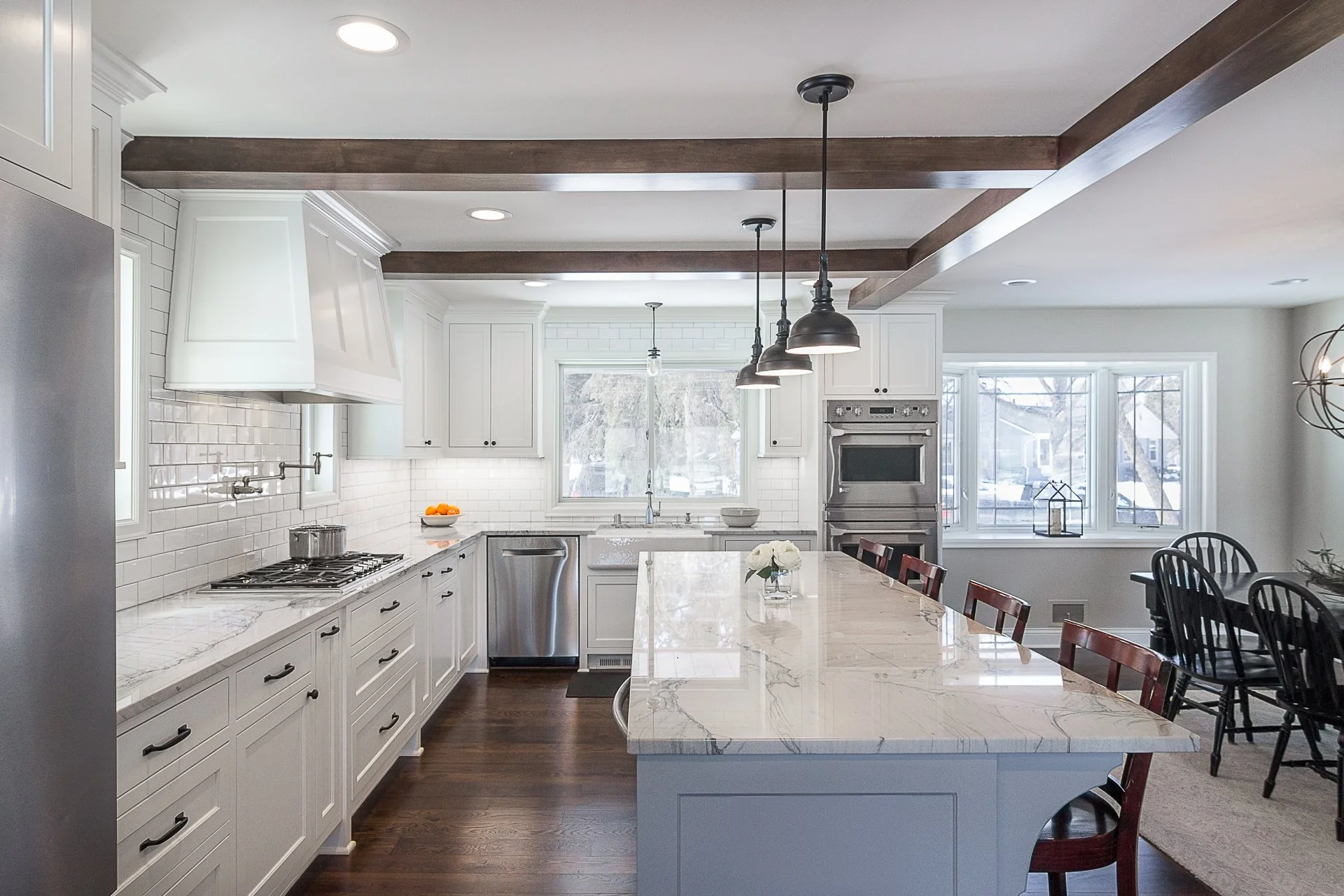 Edina custom kitchen remodel, white cabinets, quartzite countertops, rustic wooden beams, black pendant lights.