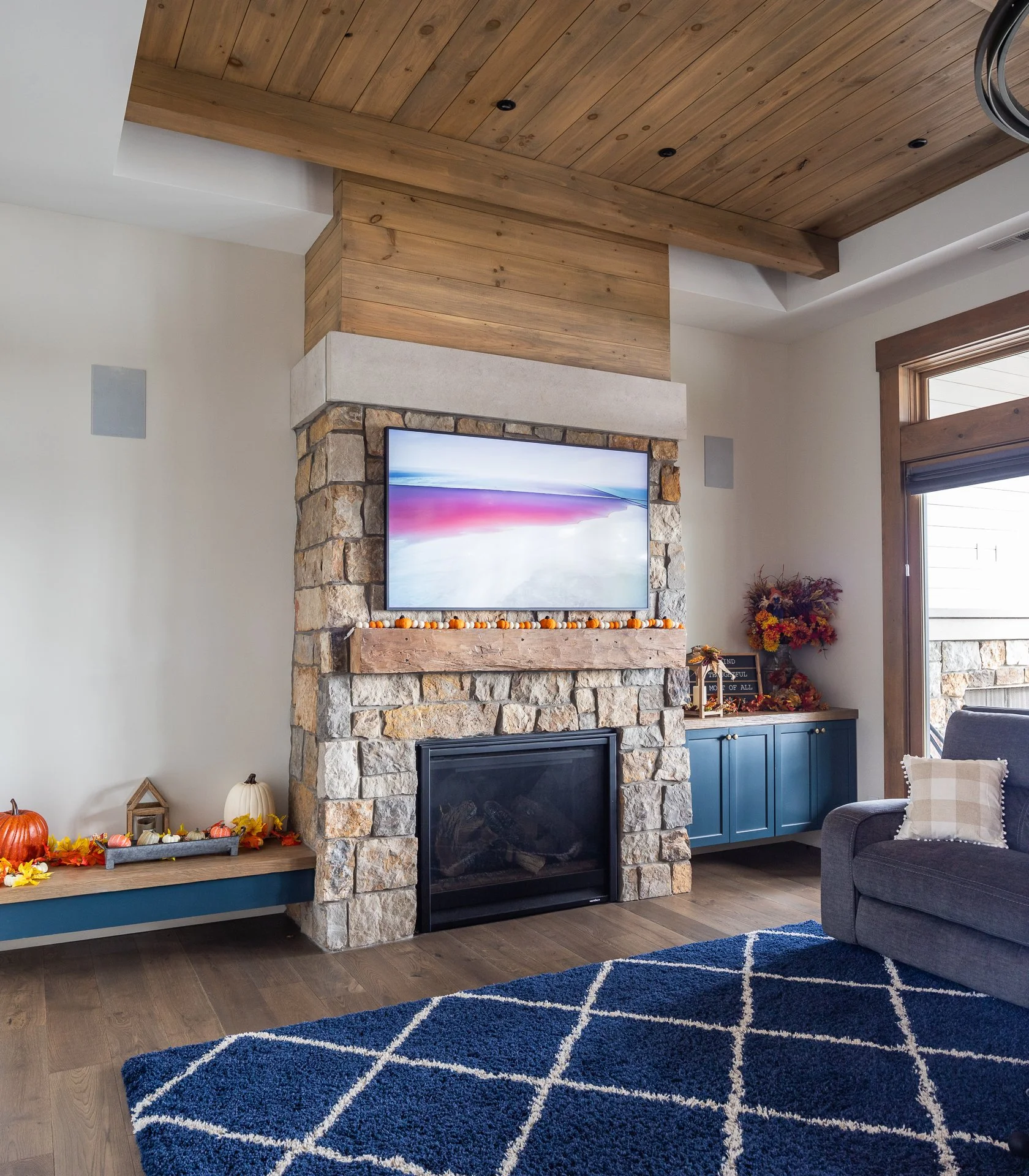 Custom blue built-in cabinets surrounding a stone fireplace in a vaulted living room