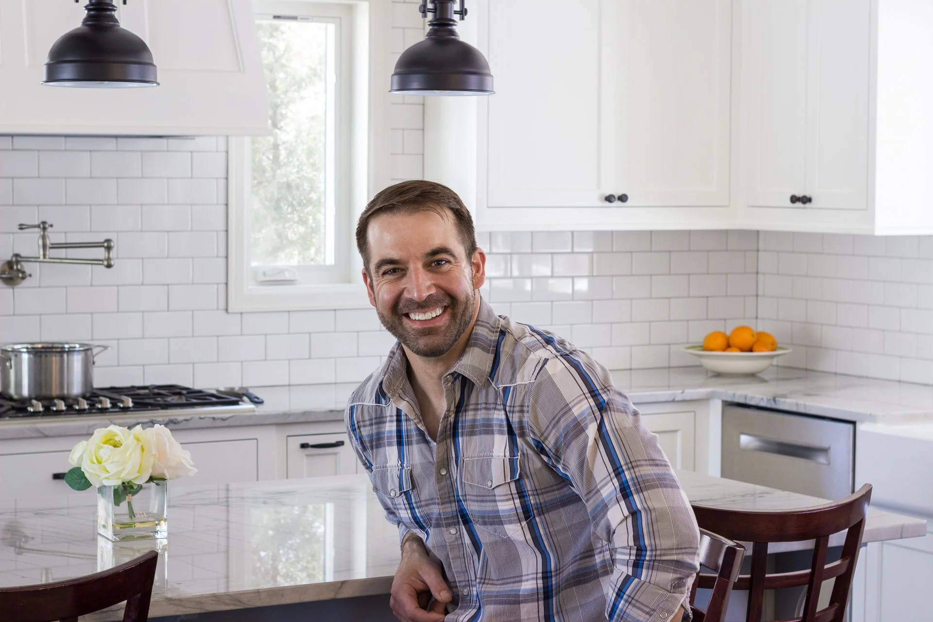 Matt Wagoner of Limitless Construction at a Twin Cities remodeling project. An Edina Kitchen remodel with white cabinets, quartzite countertops and black pendant lights.