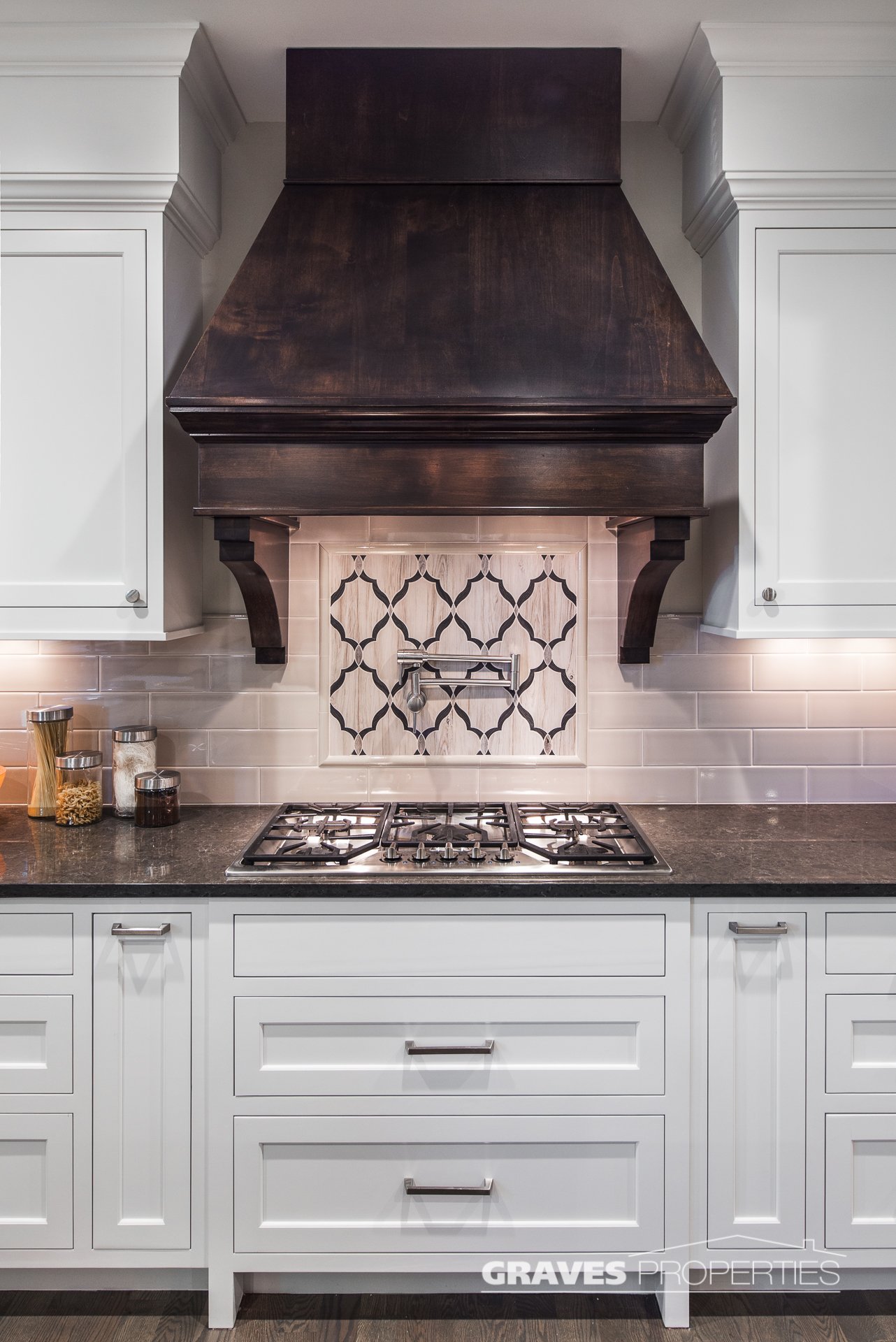 dark wood hood vent, granite countertops, mosaic tile backsplash, in Shorewood, Minnesota home.
