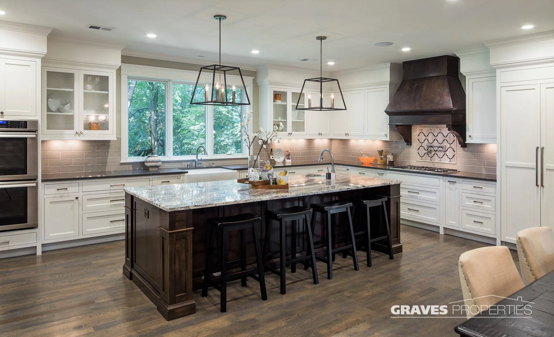 Shorewood custom kitchen remodel. dark wood island and hood vent, cream cabinets, dark granite countertops, candle pendants, mosaic backsplash