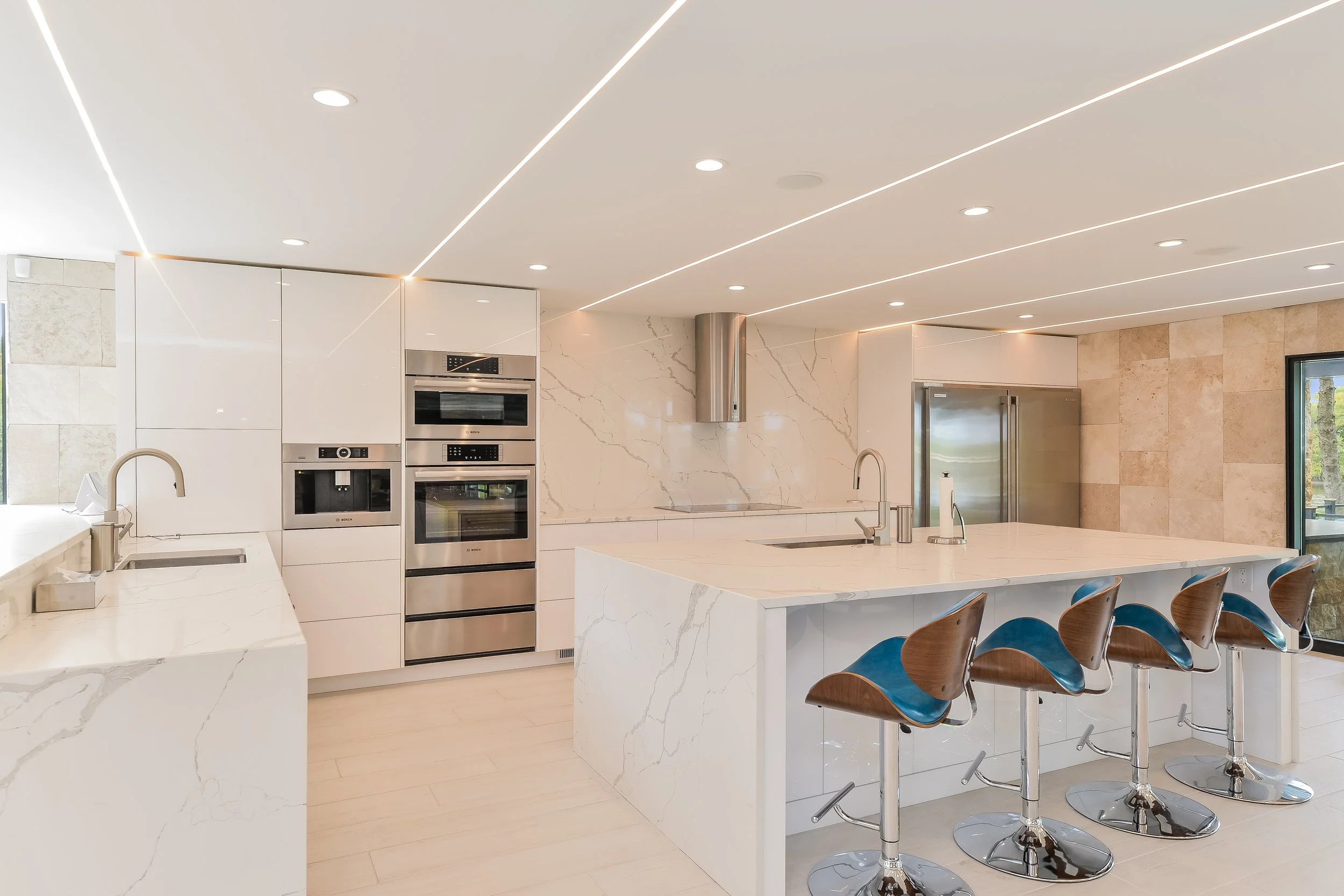 Modern white kitchen with custom cabinetry, waterfall island, and integrated appliances