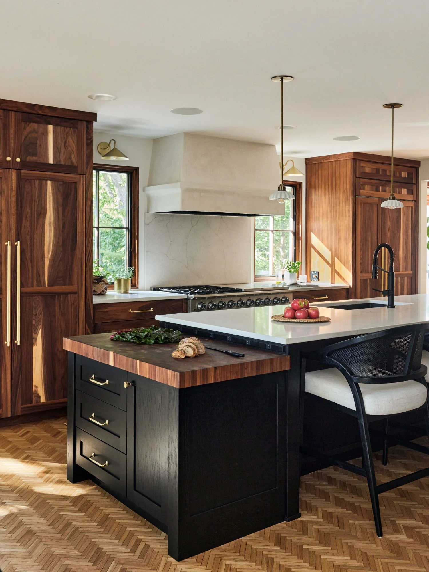 Custom kitchen remodel in Golden Valley, MN, featuring walnut cabinetry, a black island, butcher block prep surface and herringbone wood floors.