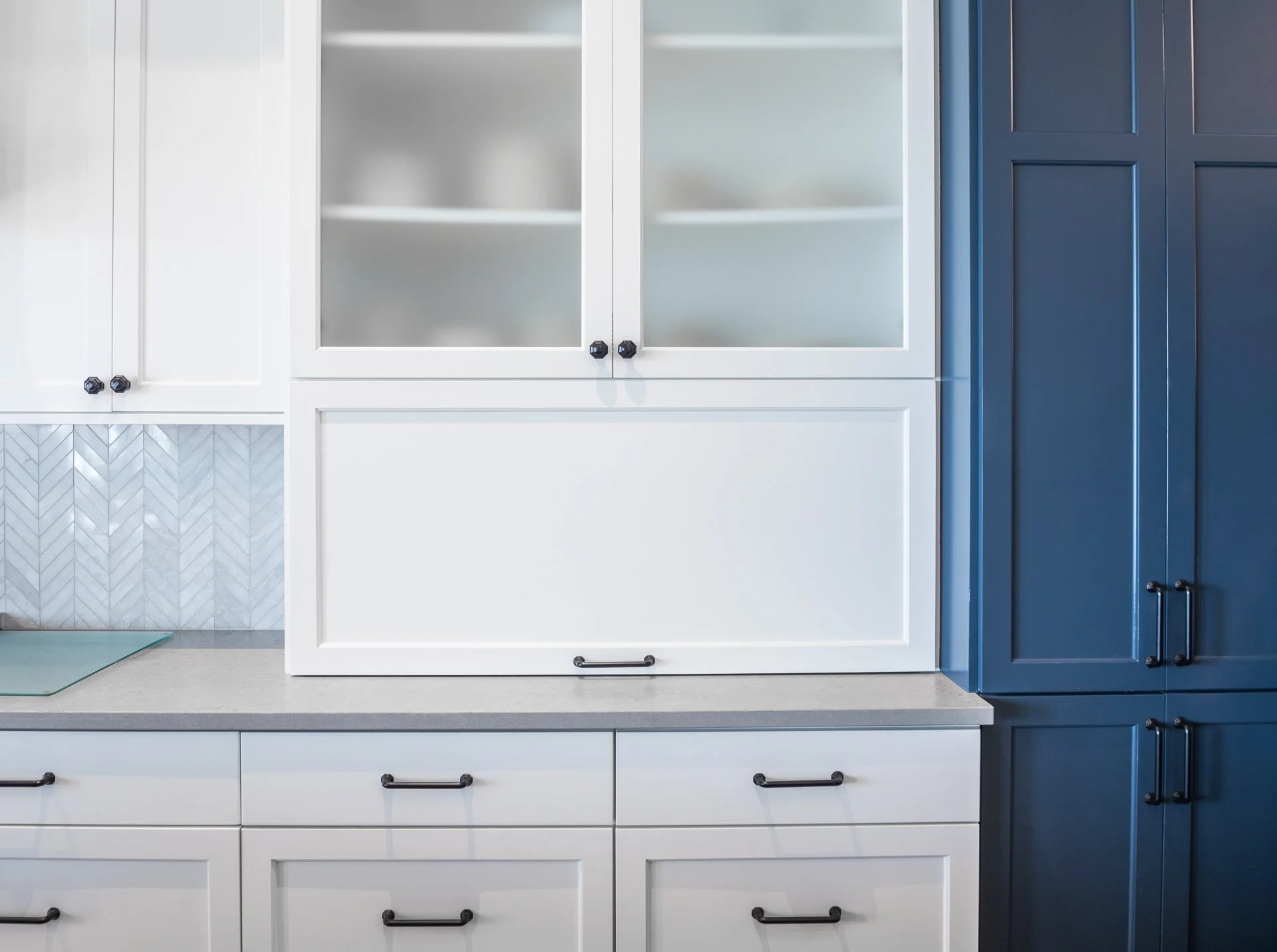 White custom cabinetry with glass-front upper cabinets, appliance garage, and navy side cabinet