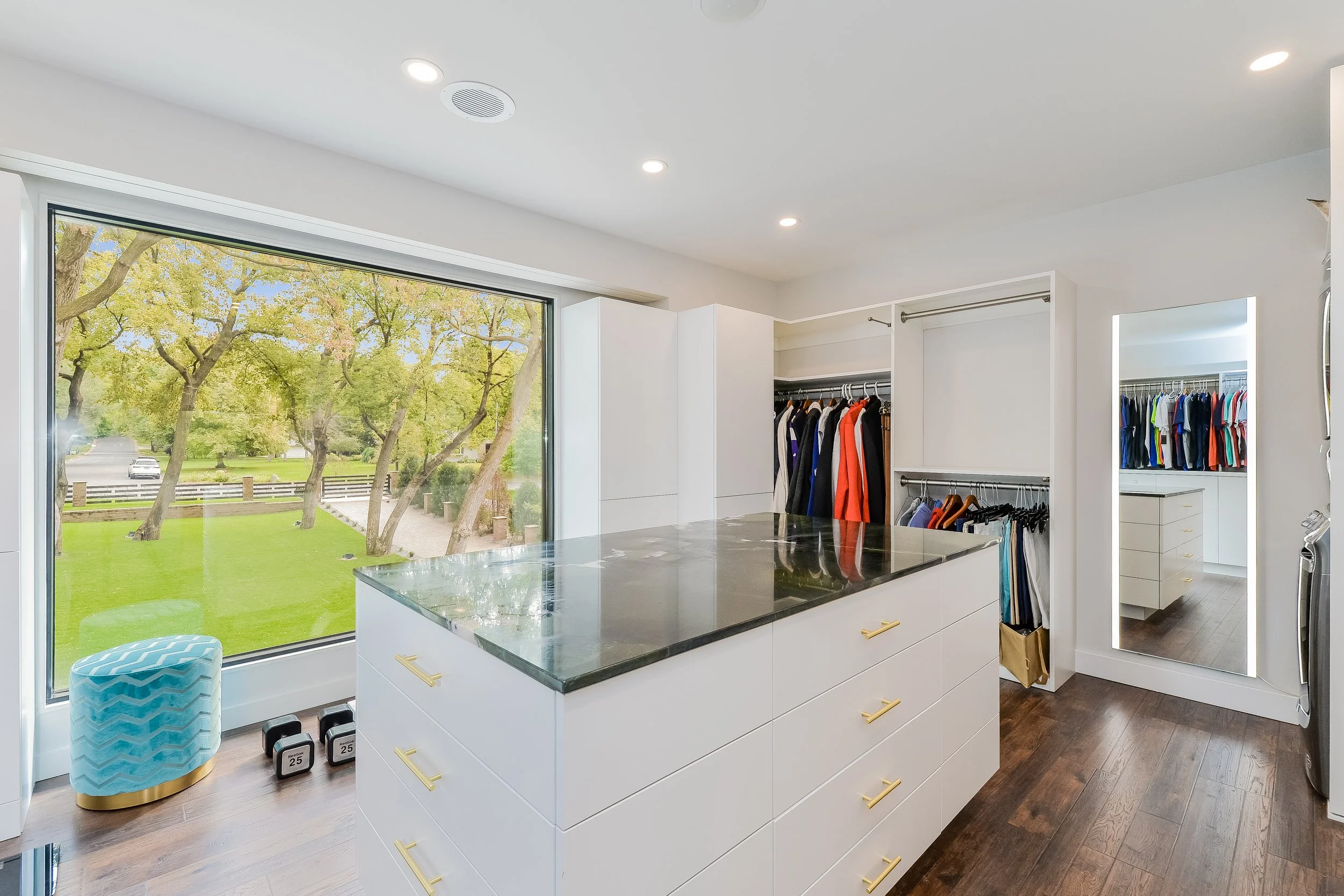 Custom white walk-in closet with center island, glass countertop, and built-in clothing storage