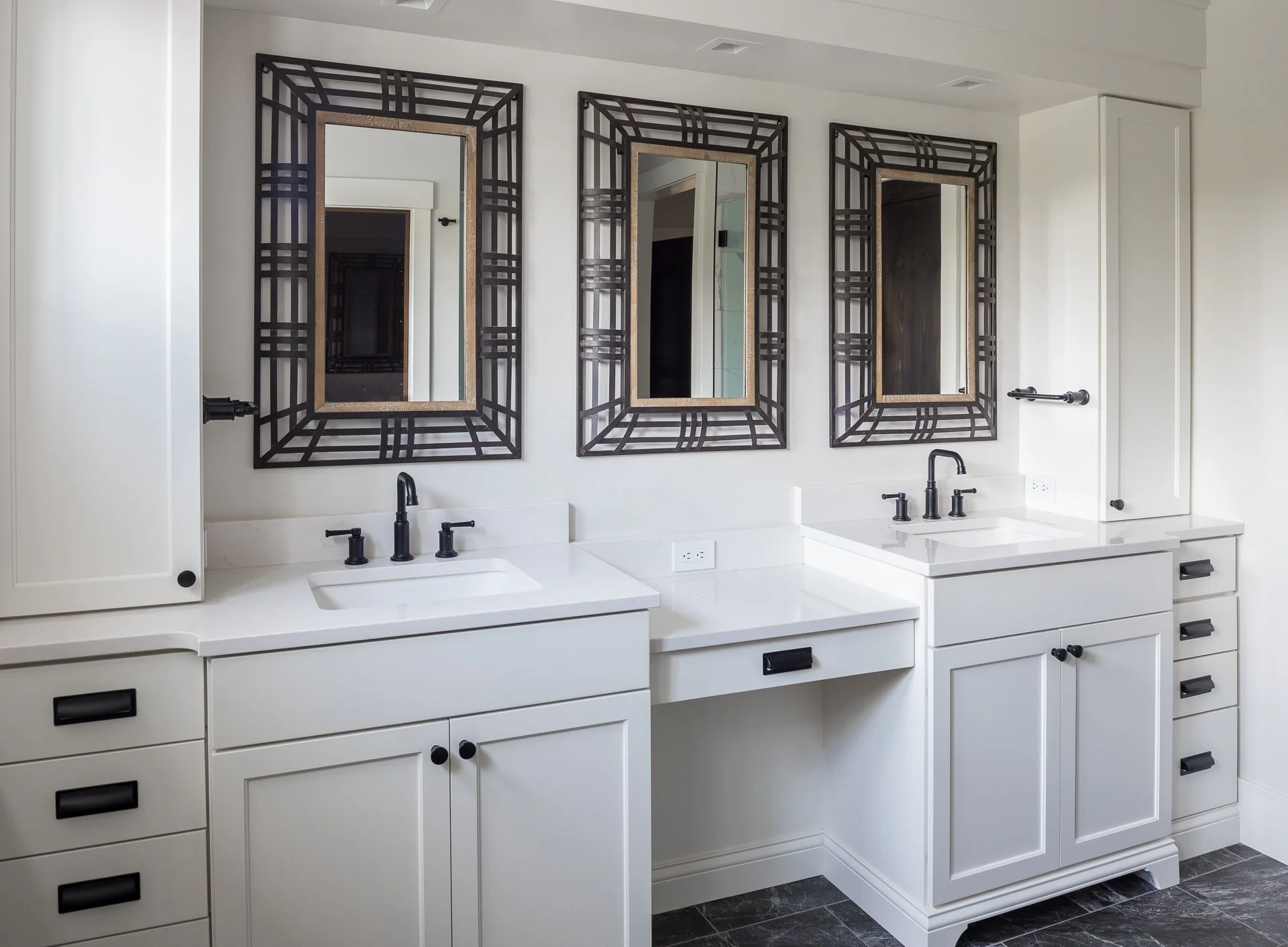 White custom double vanity with dark countertops, vessel sinks, and framed mirrors