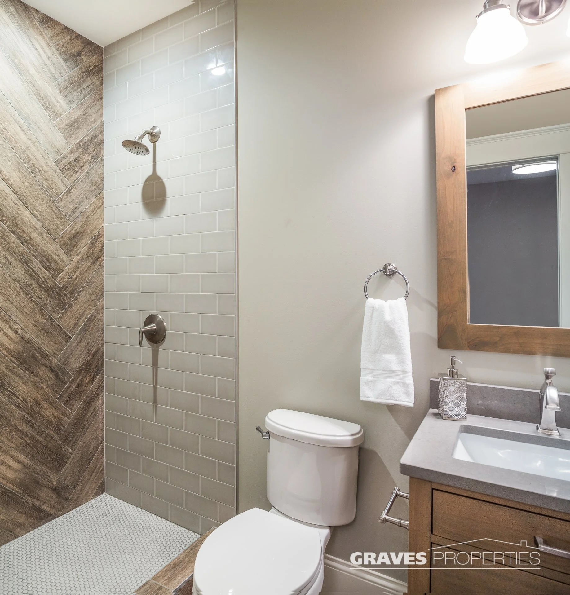 Bathroom with light beige colored tile, and wood tile, with a rustic wood mirror frame.