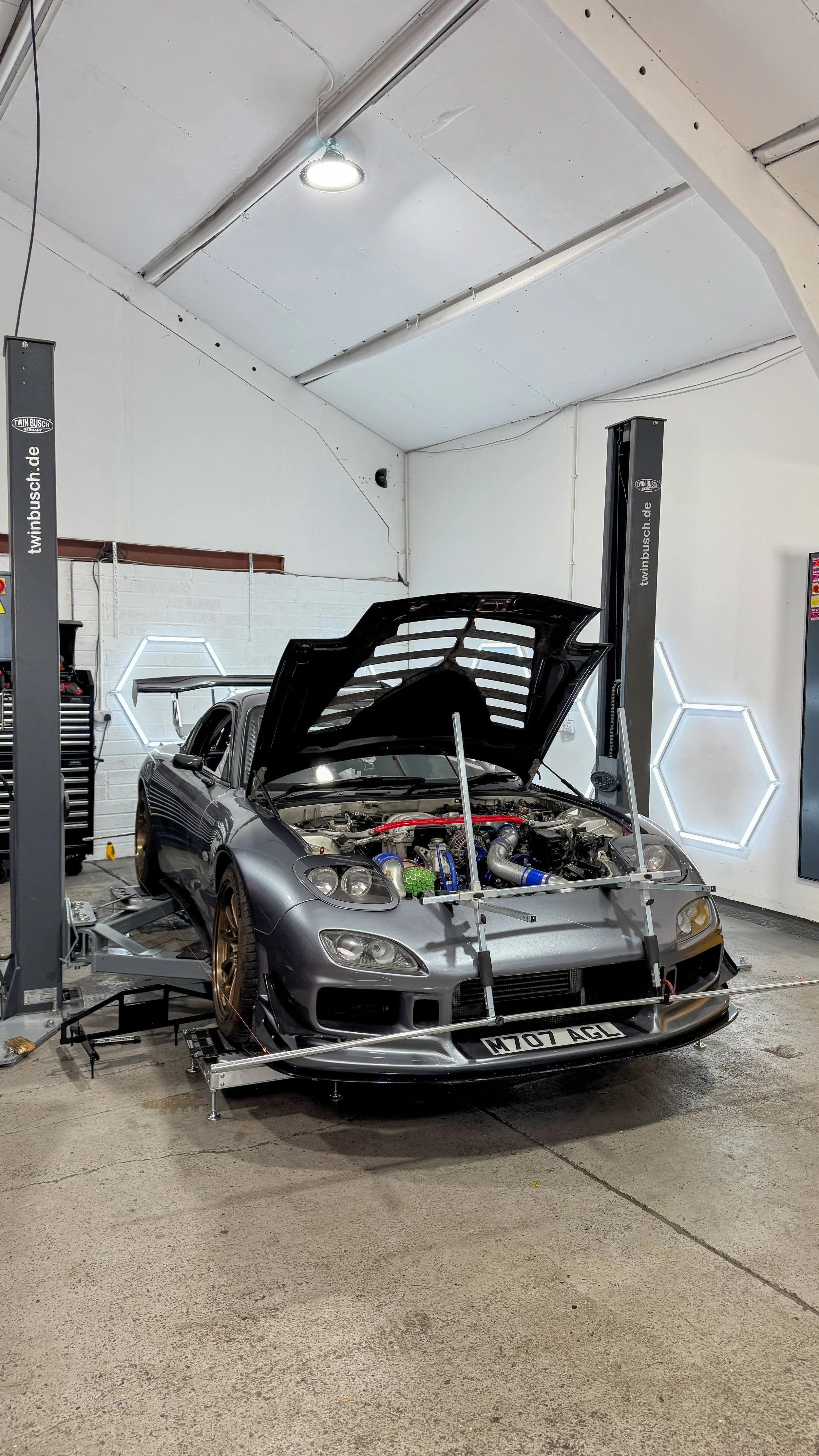 Mazda RX-7 track car undergoing four-wheel geometry and string alignment on corner weight scales