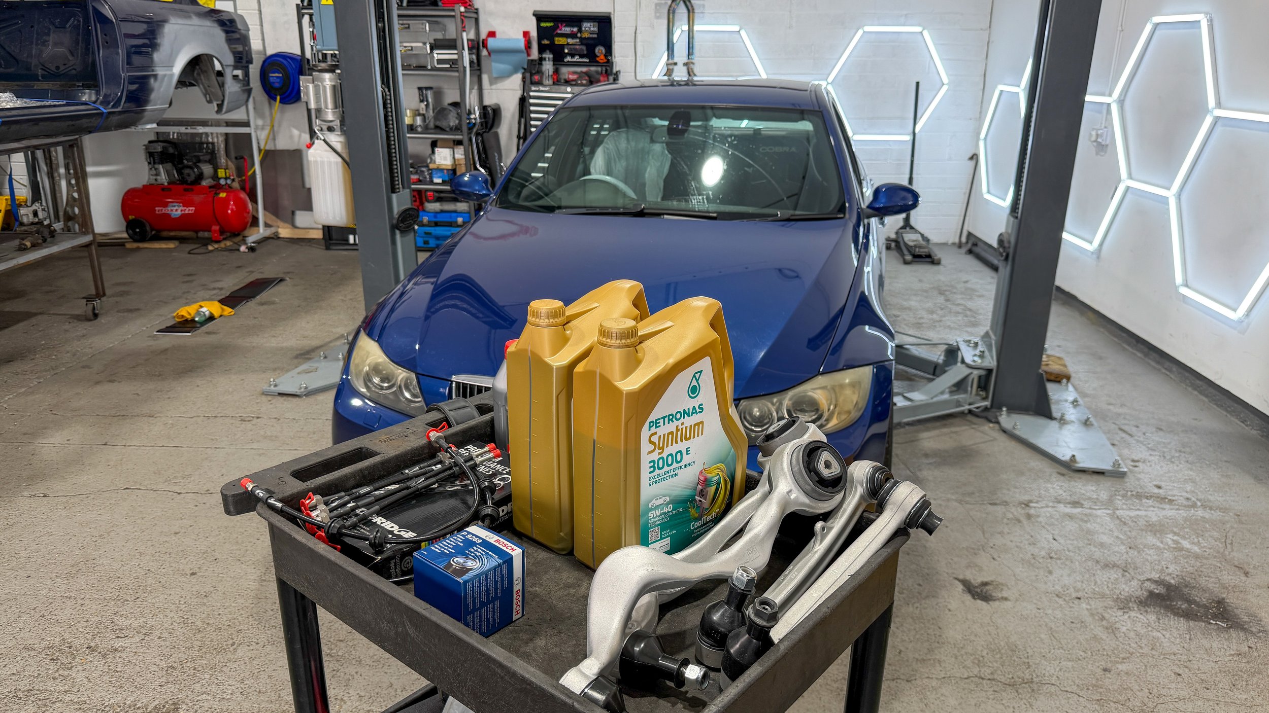 BMW E90 with adjustable control arms, braided brake lines, oil and service parts prepared for installation