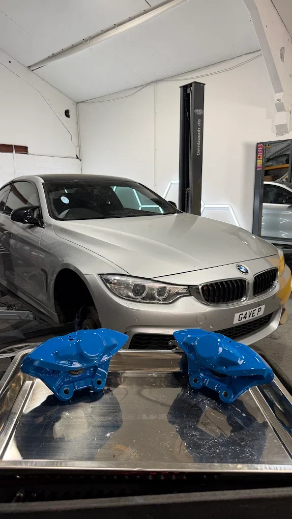 BMW 435i track car with freshly painted blue brake calipers during brake upgrade work