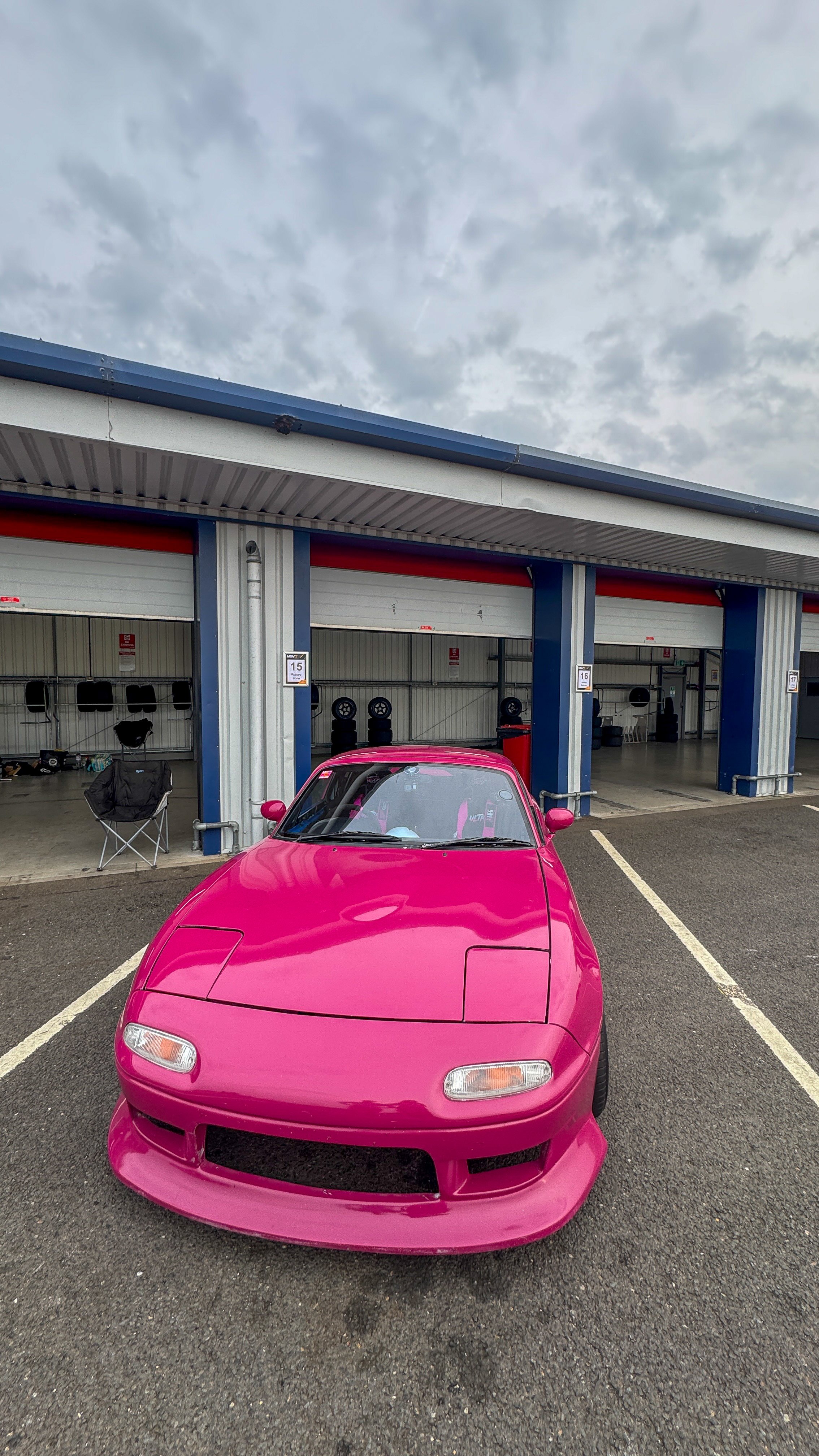 Pink Mazda MX-5 MK1 track car parked outside the garages at Bedford autodrome race circuit
