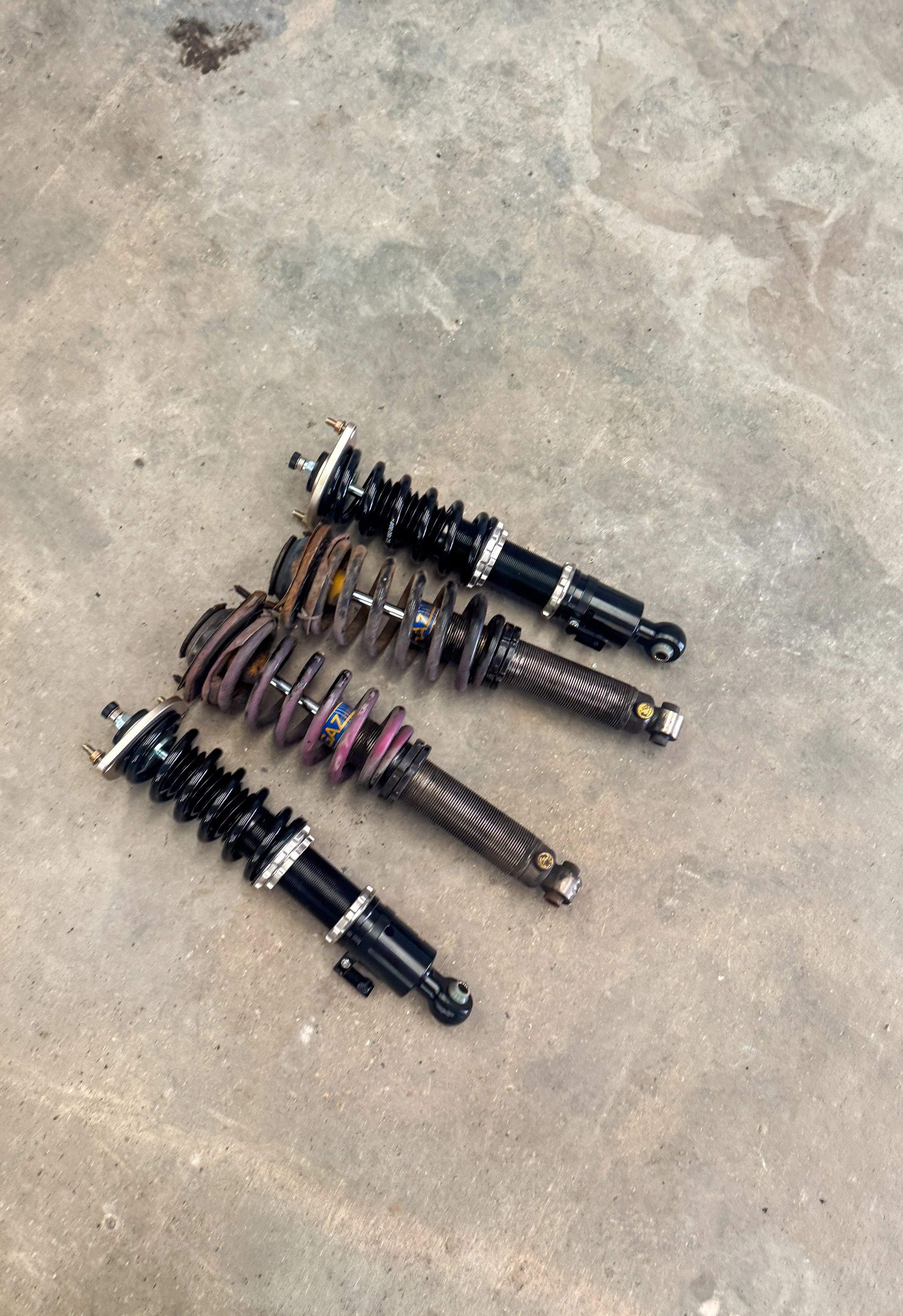 Old Mazda MX-5 track car coilovers alongside new BC Racing coilovers ready for installation