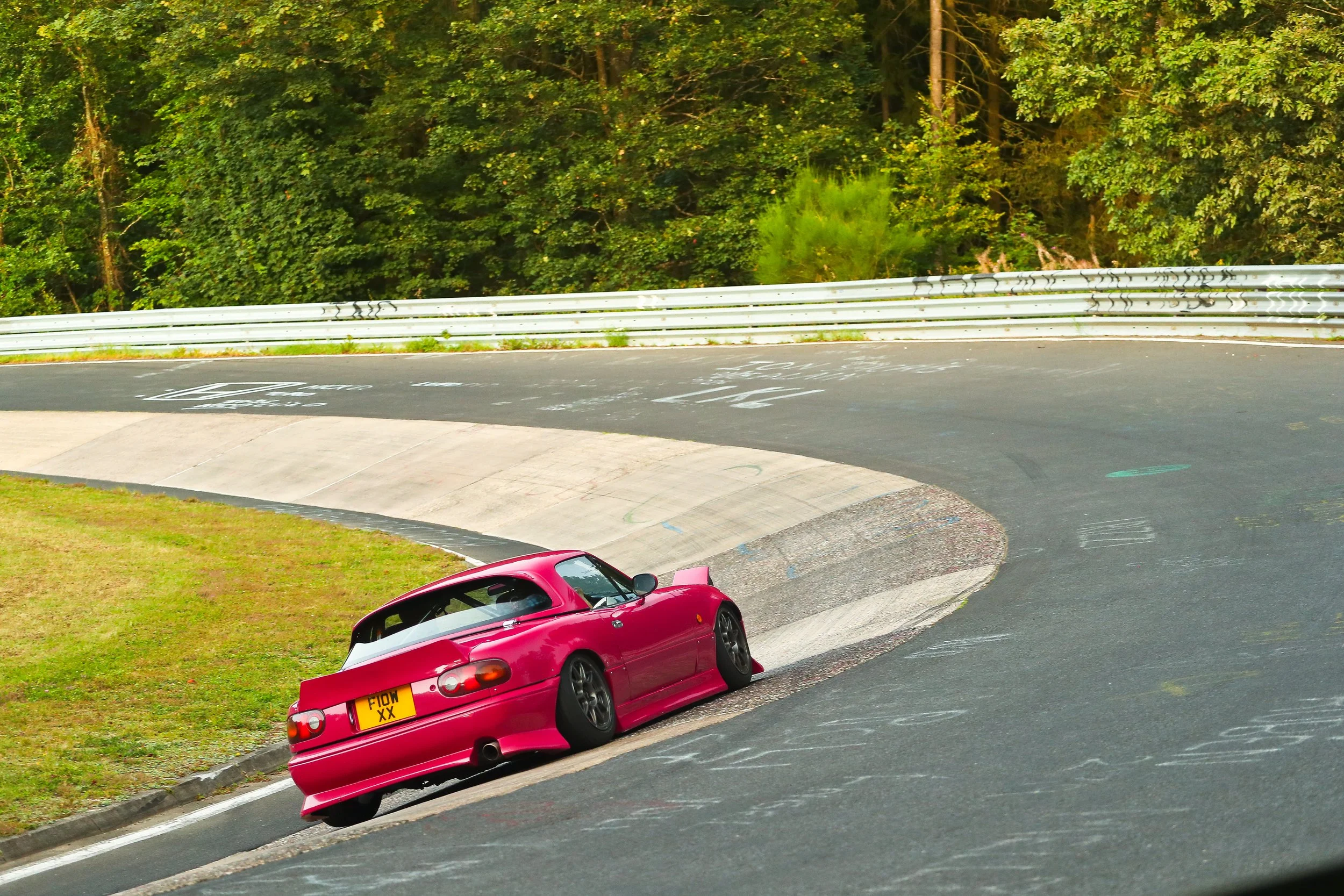 Pink Mazda MX-5 MK1 track car driving through the karussell at the Nurburgring
