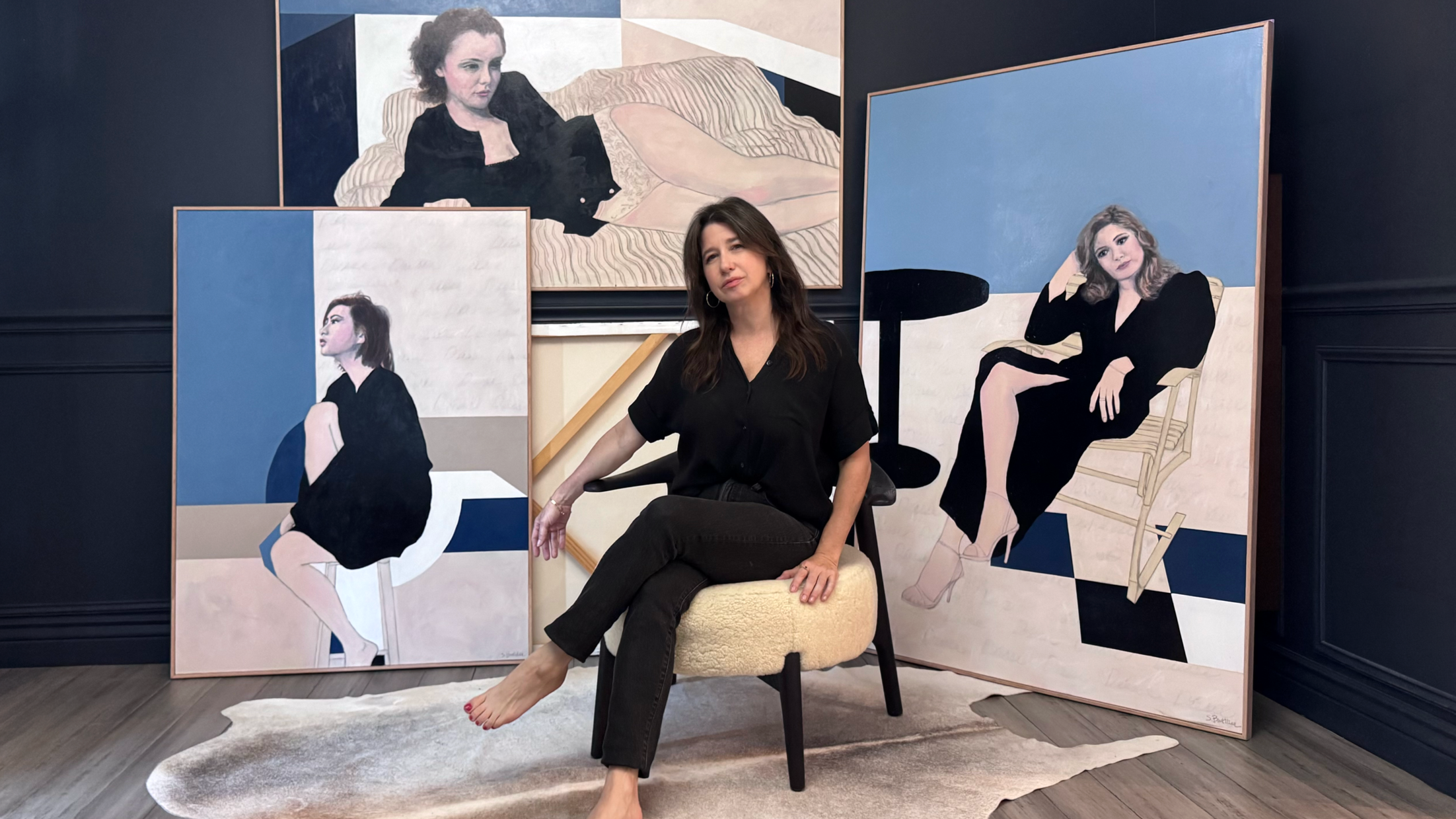 Artist Shannon Boutilier seated in her studio surrounded by large-scale paintings from The Goddess Series.