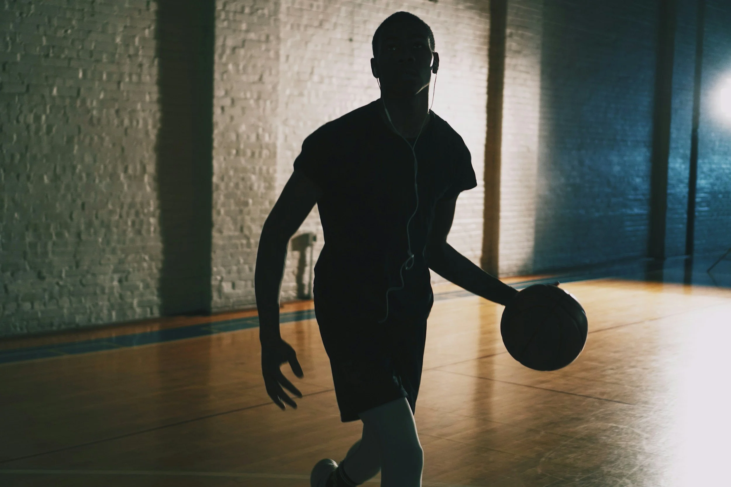 Basketball athlete holding a basketball while walking through a gym.