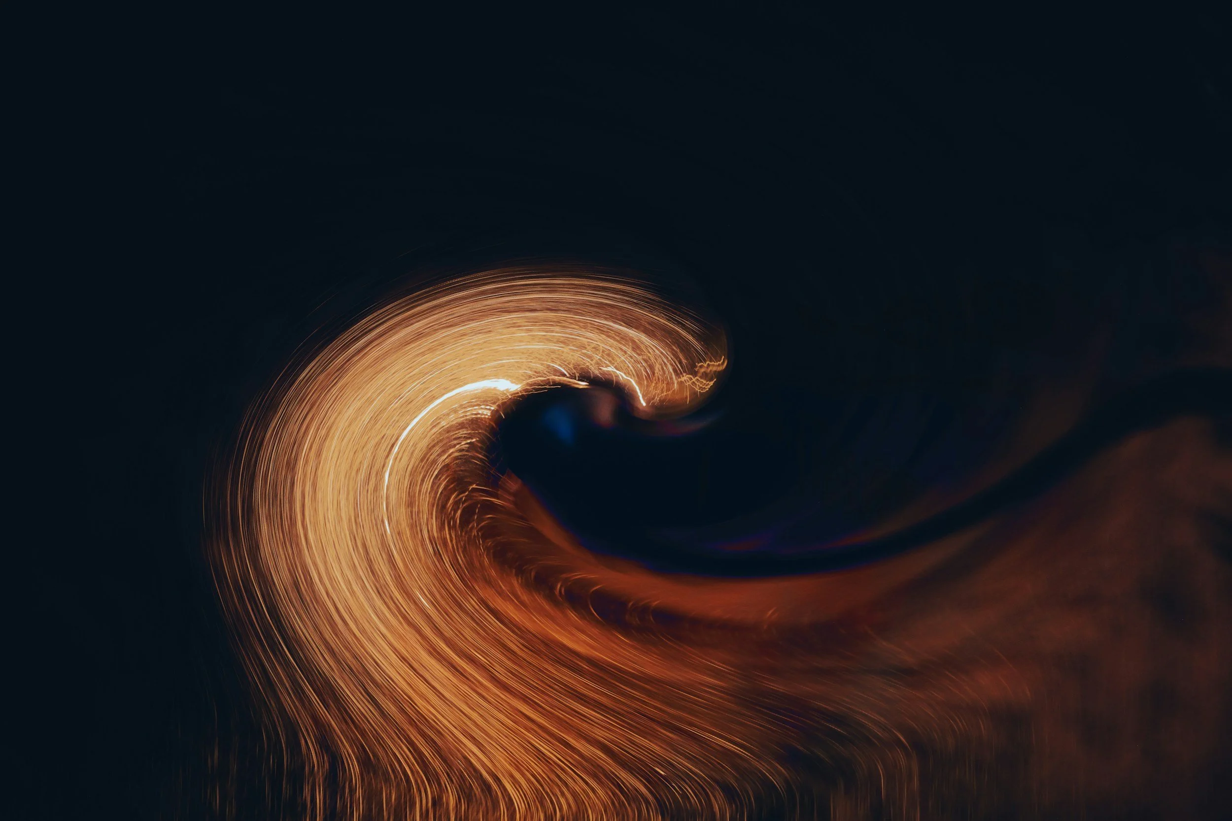 Swirling pattern of sparks or light trails against a dark background.