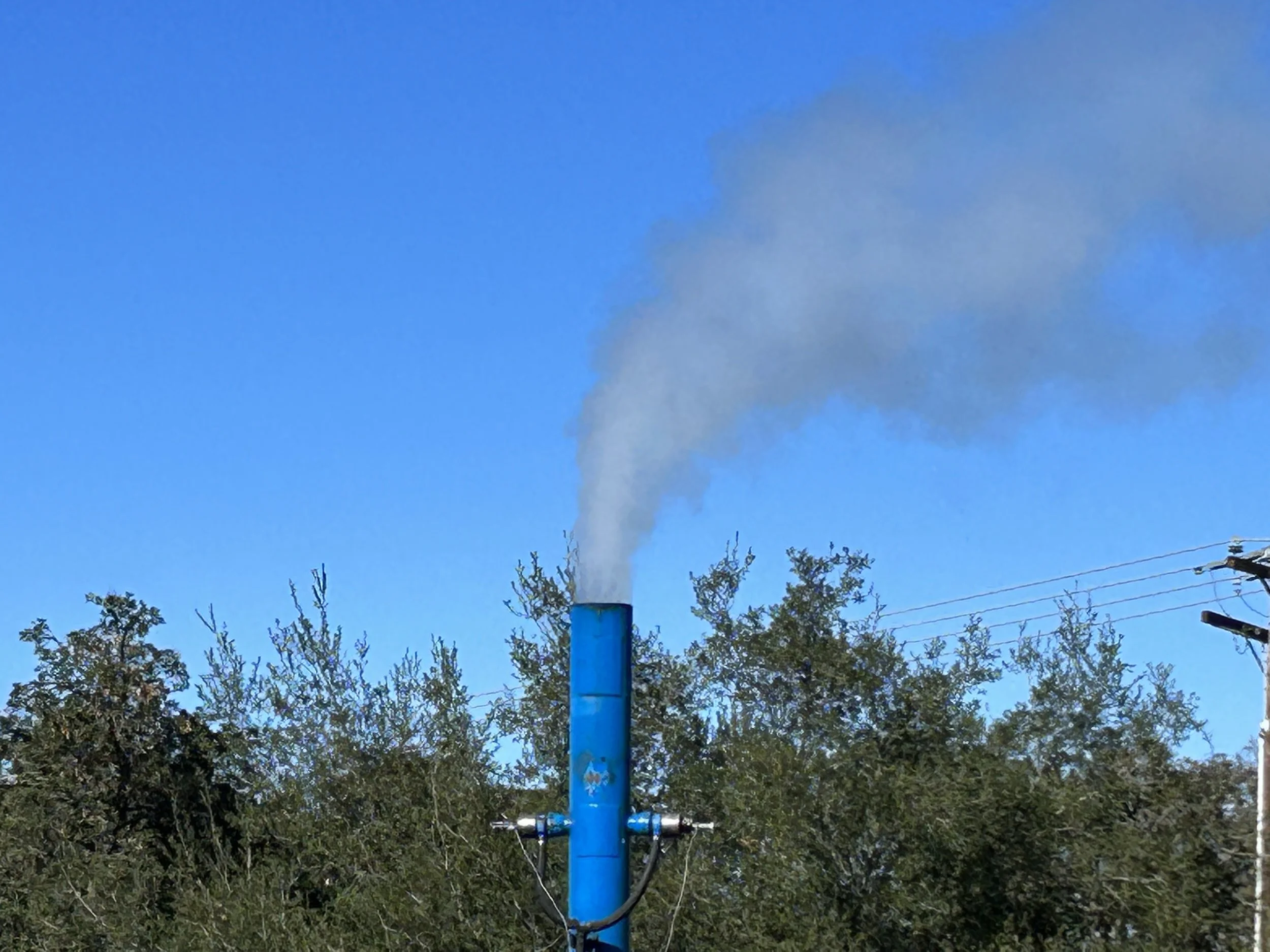 A blue smoking chimney pipe set against a clear blue sky, with trees below. | Method 9