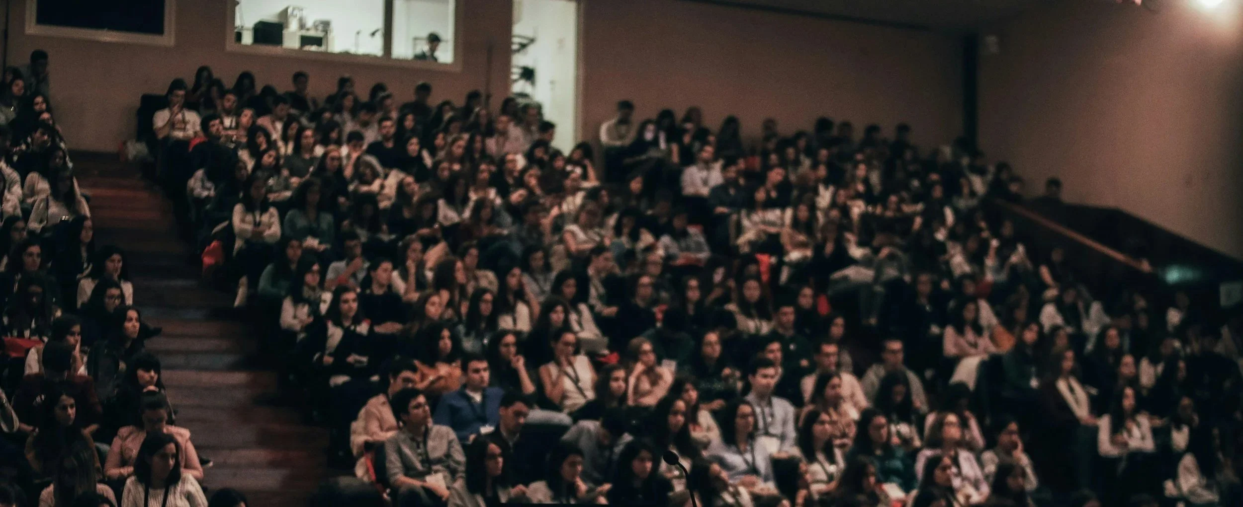 A large group of people sitting in an auditorium, attending a presentation or event.