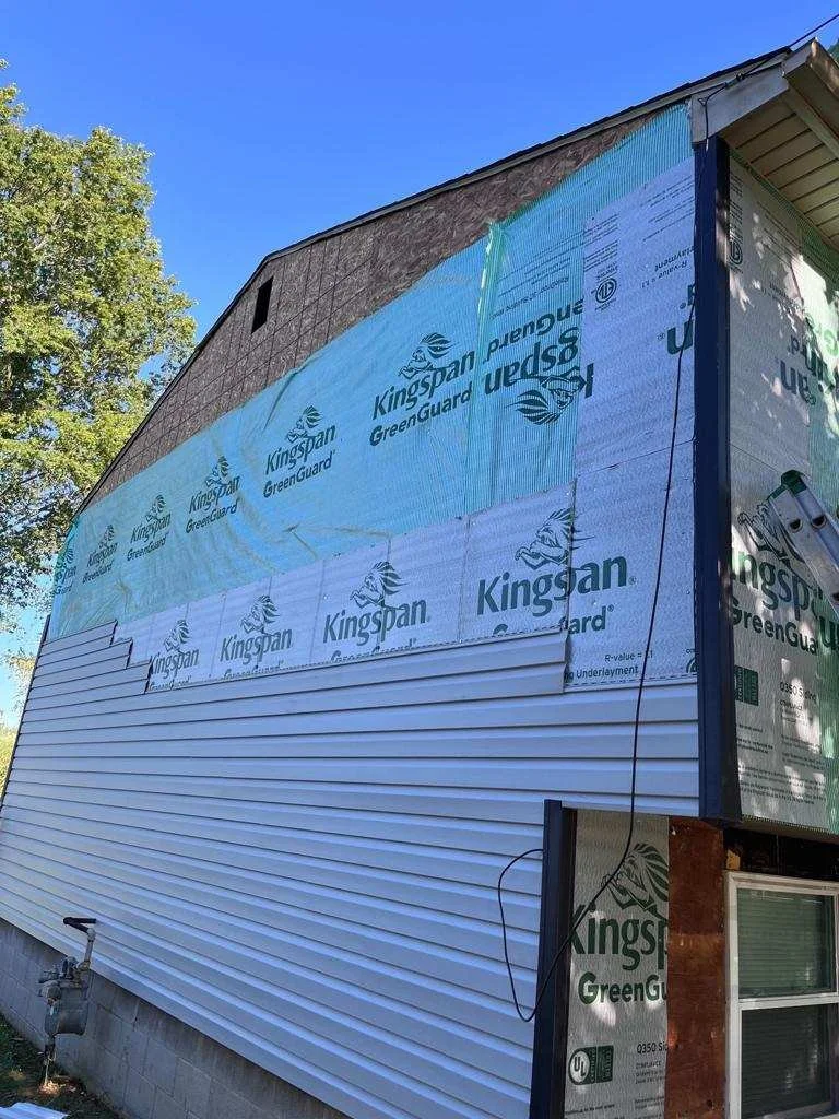 Exterior renovation showing building wrap, insulation and new siding installation.