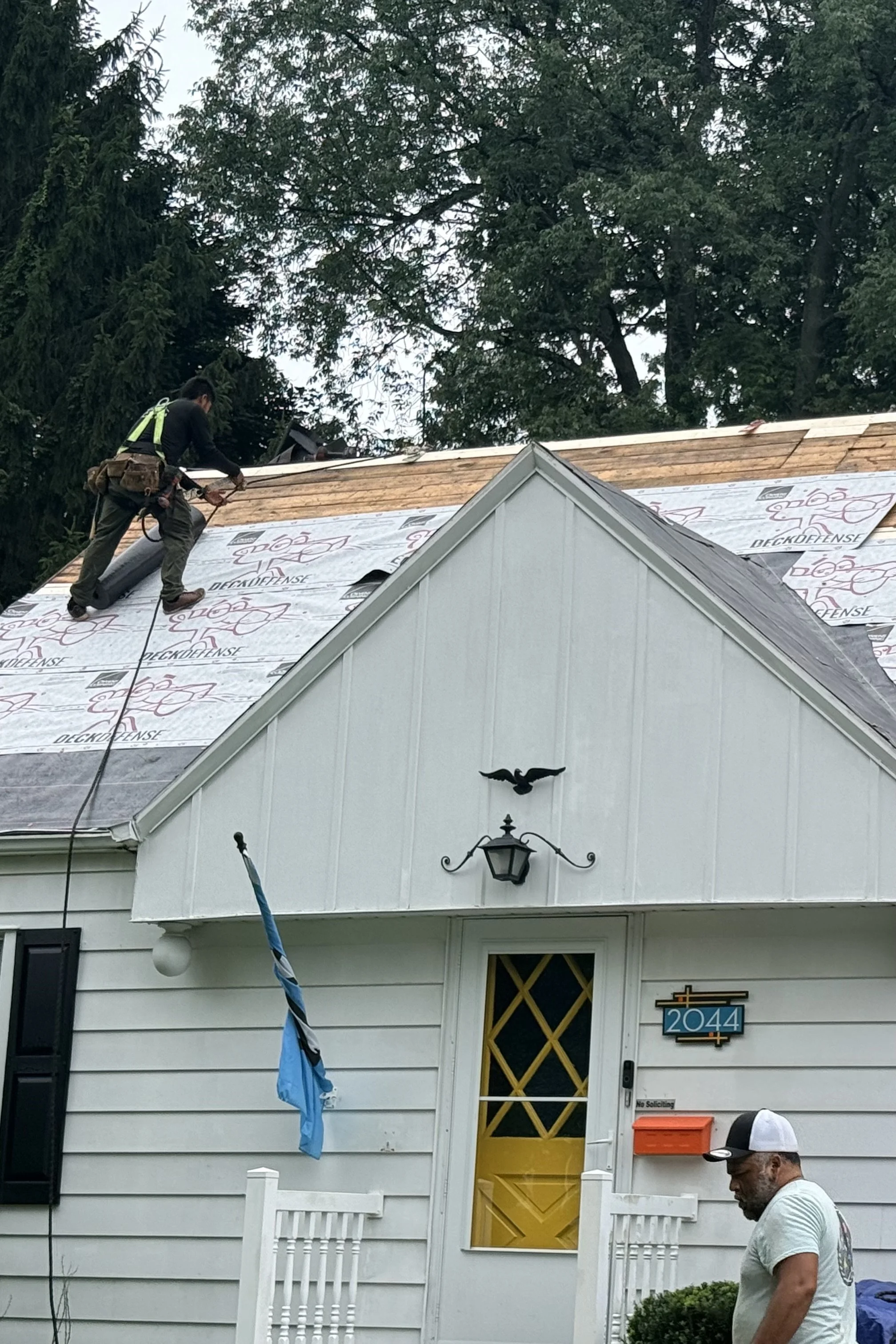 Roofing contractor installing underlayment during a residential roof replacement.