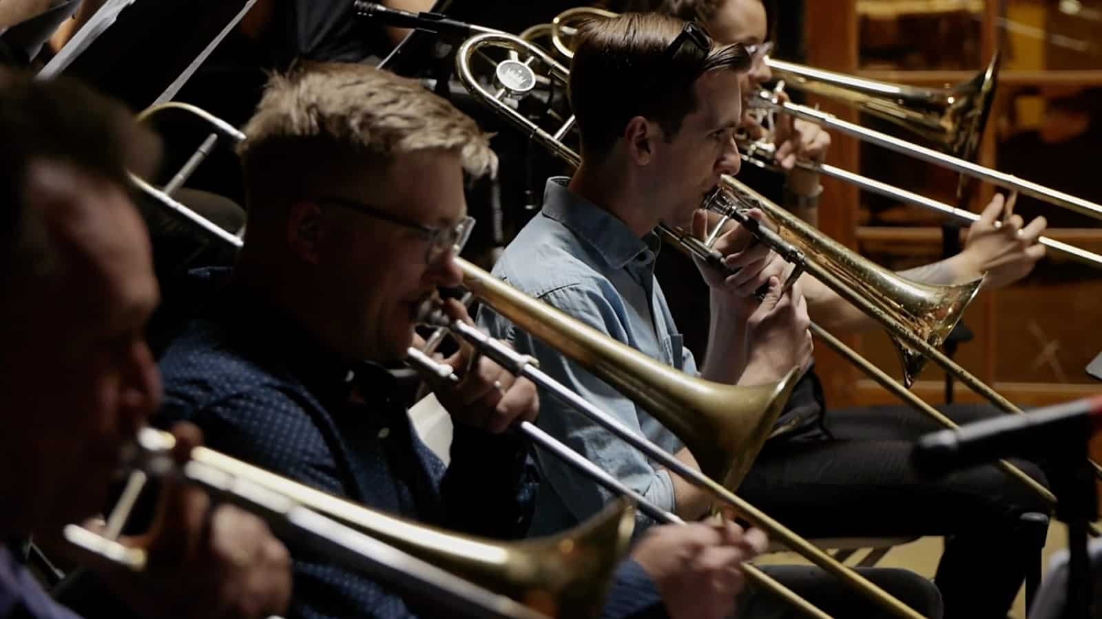 A group of musicians playing trombones during a rehearsal or performance.