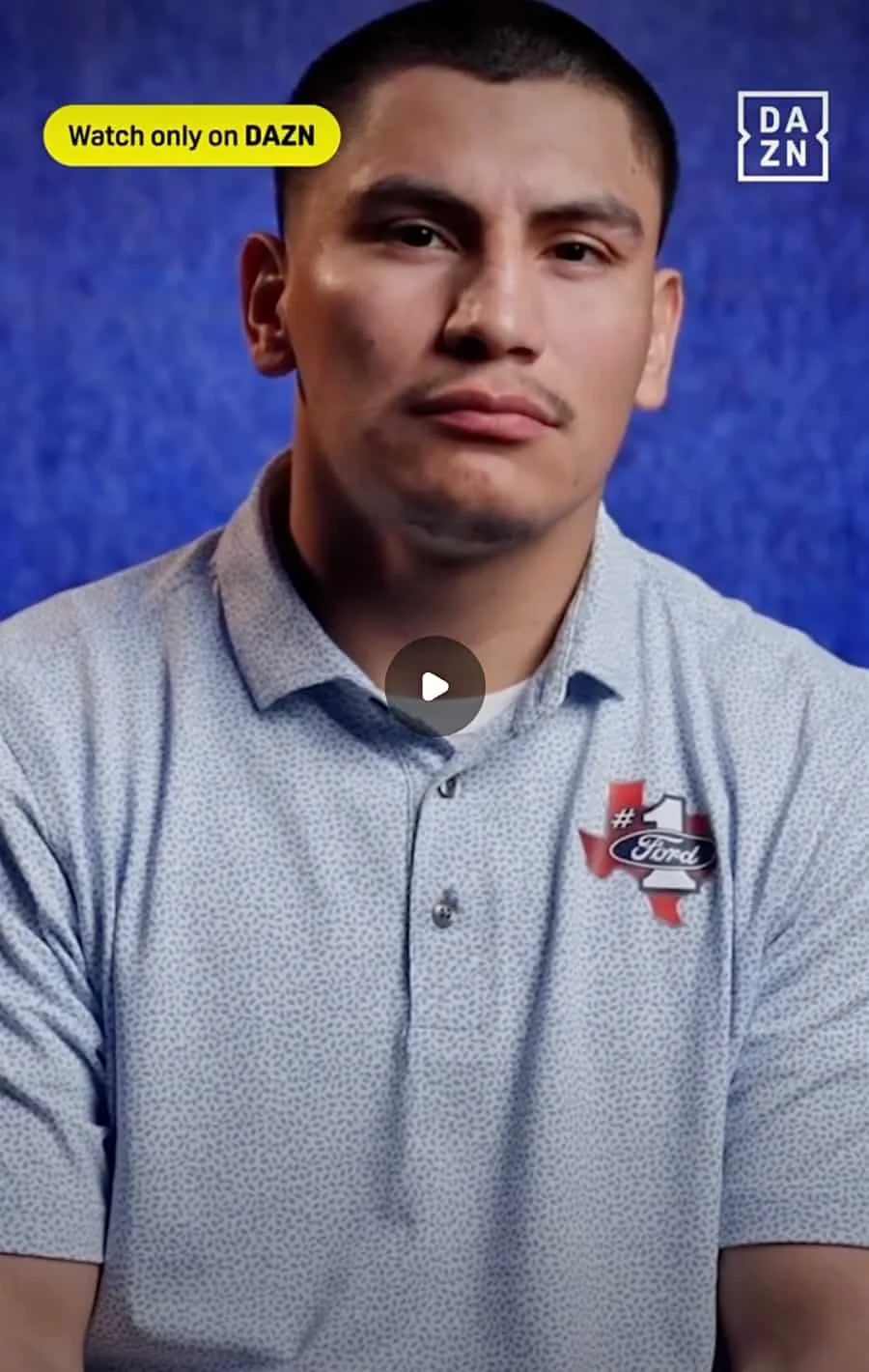 A young man with short dark hair wearing a light-colored, patterned button-up shirt with a 'Ford' logo patch on the left chest, seated against a blue background, with a yellow banner in the top left corner that reads 'Watch only on DAZN' and a DAZN logo in the top right corner.