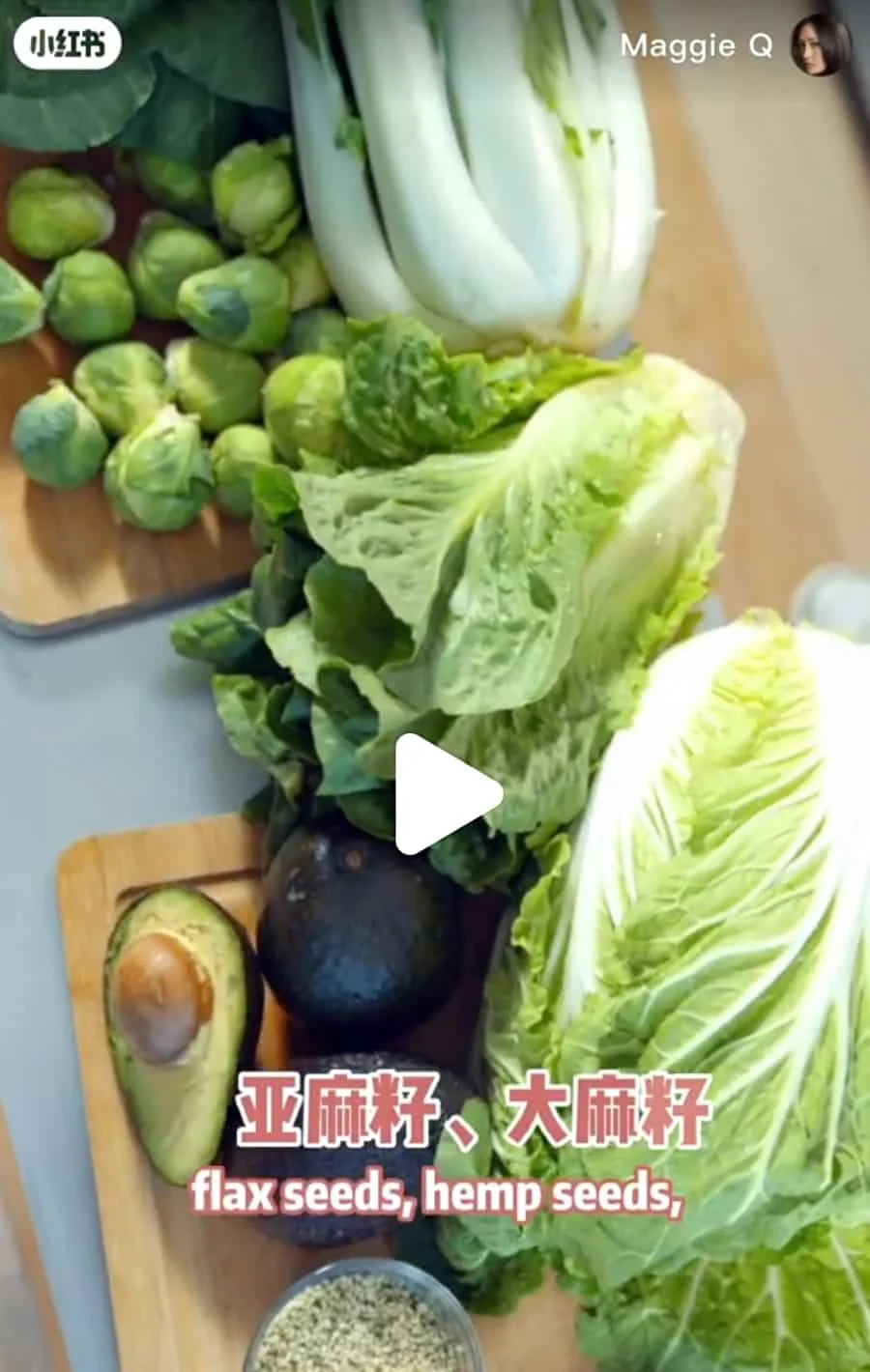 Assorted fresh vegetables including Brussels sprouts, heads of lettuce, an avocado, on wooden cutting boards, with a bowl of seeds.