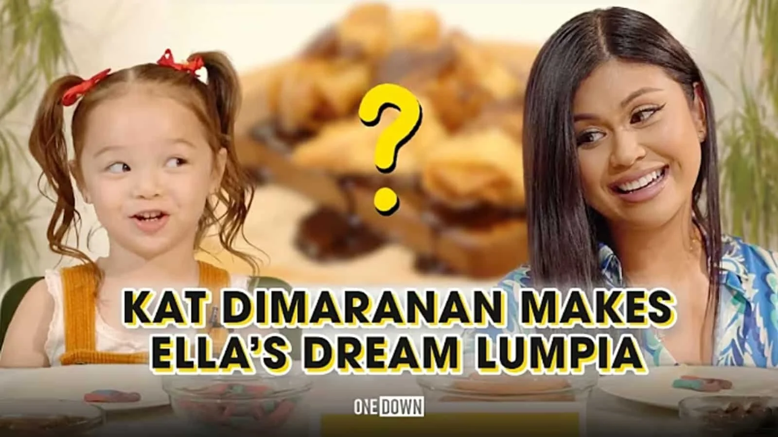 A young girl with red hair in pigtails and a woman with long dark hair sitting at a table with plates of food, with a yellow question mark and the text 'Kat Dimaranan Makes Ella's Dream Lumpia' overlayed on the image.