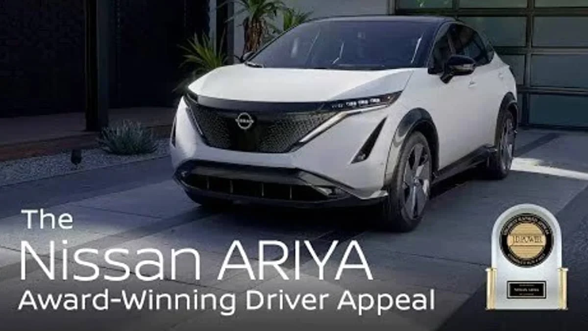 White Nissan Ariya electric vehicle parked in a driveway, with a badge and text celebrating its award-winning driver appeal.