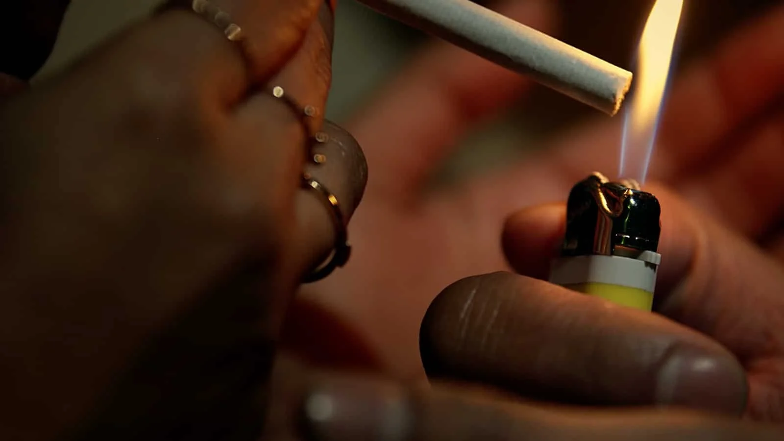 Close-up of a person lighting a cigarette with a lighter