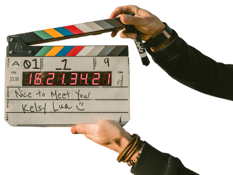 Clapperboard with handwritten note that says 'Nice to meet you! Kelsy Lua,' and a time display of 16:21:34:21.