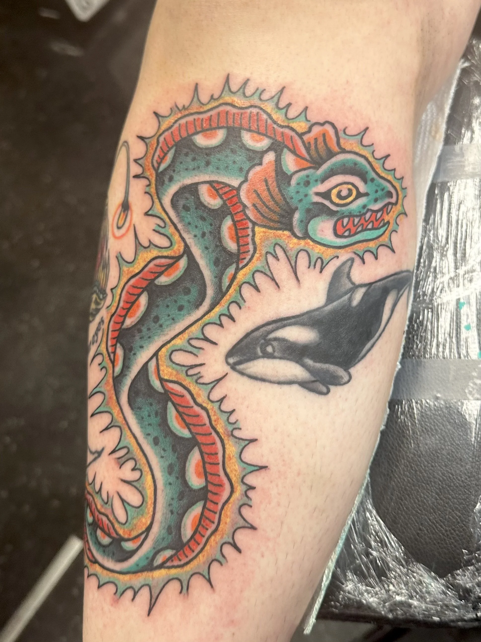 Colorful tattoo of a dragon with a fierce expression on a person's arm.