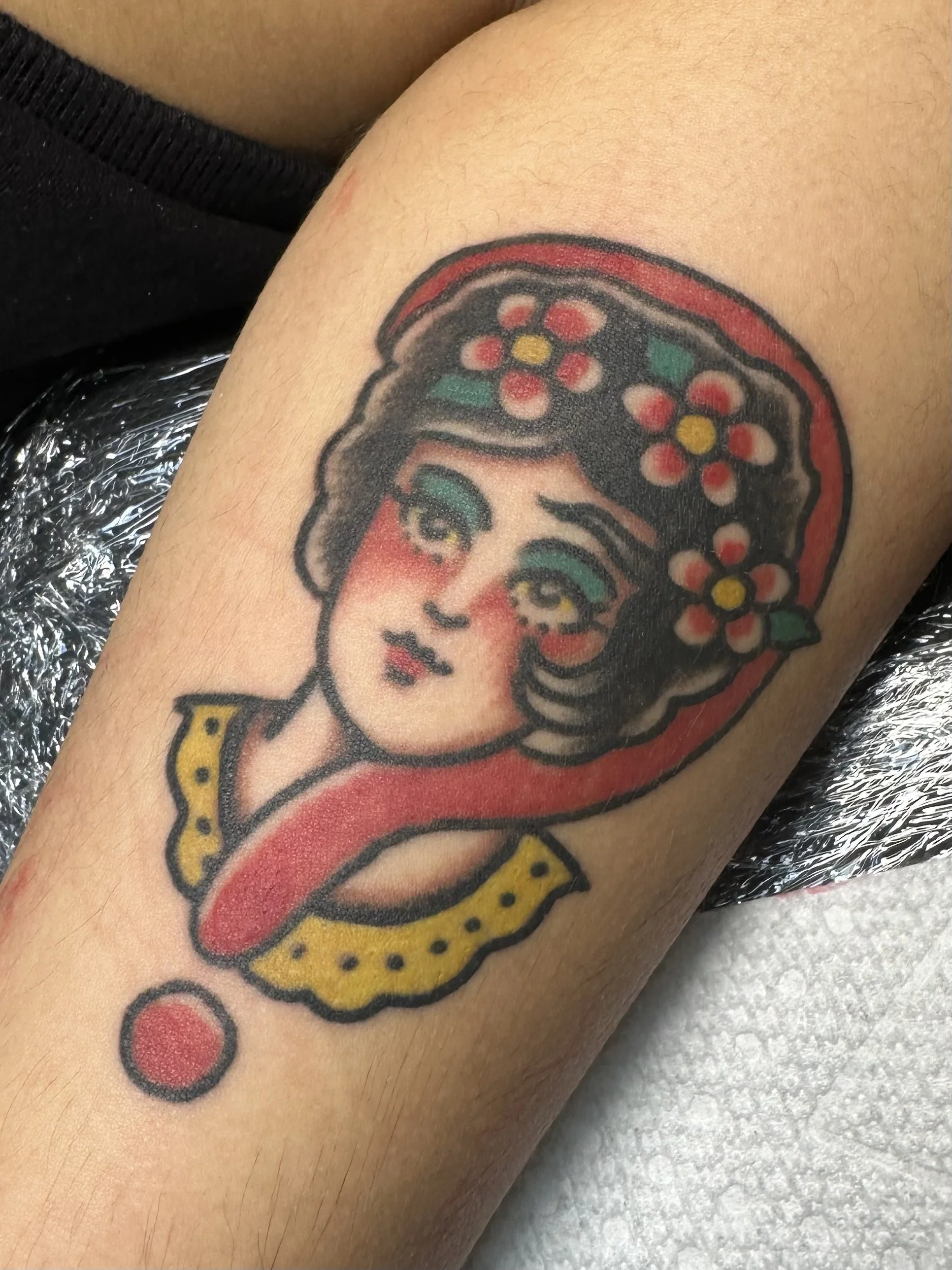 Tattoo of a woman with dark hair, wearing a traditional floral headscarf, on the person's arm.