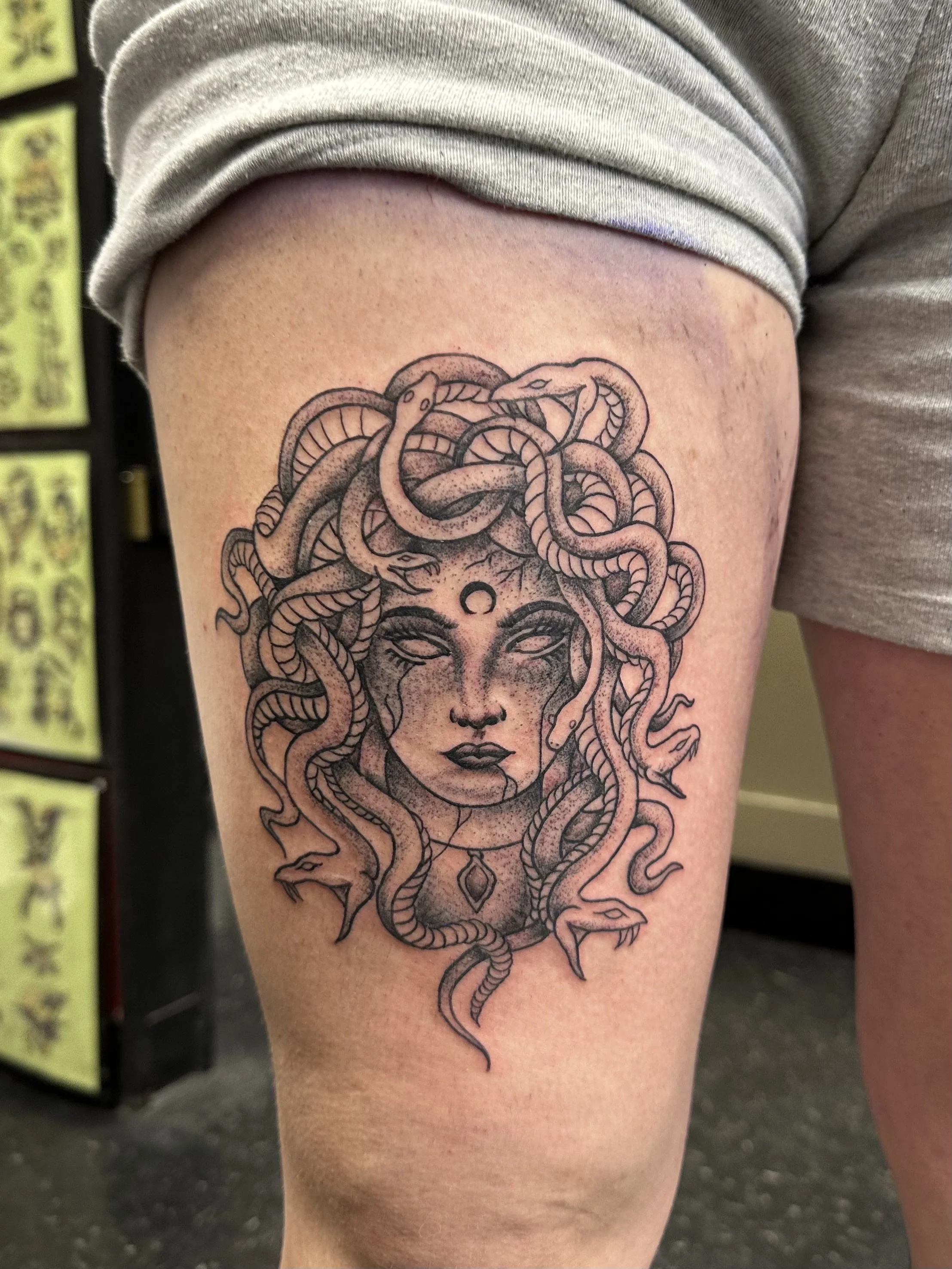 A tattoo of Medusa with snakes for hair on a person's upper thigh.